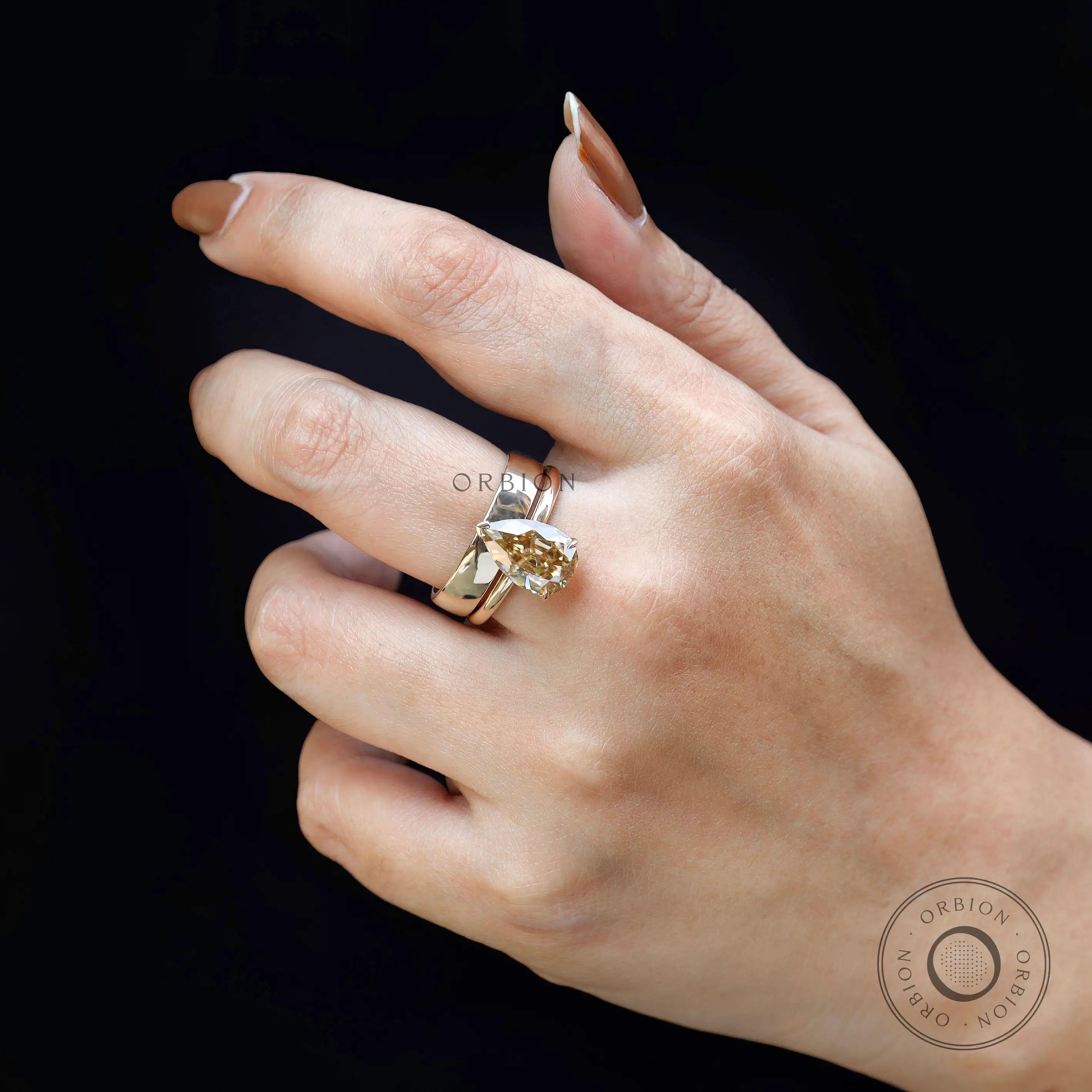 Close-up of pear champagne moissanite solitaire ring with stacked band