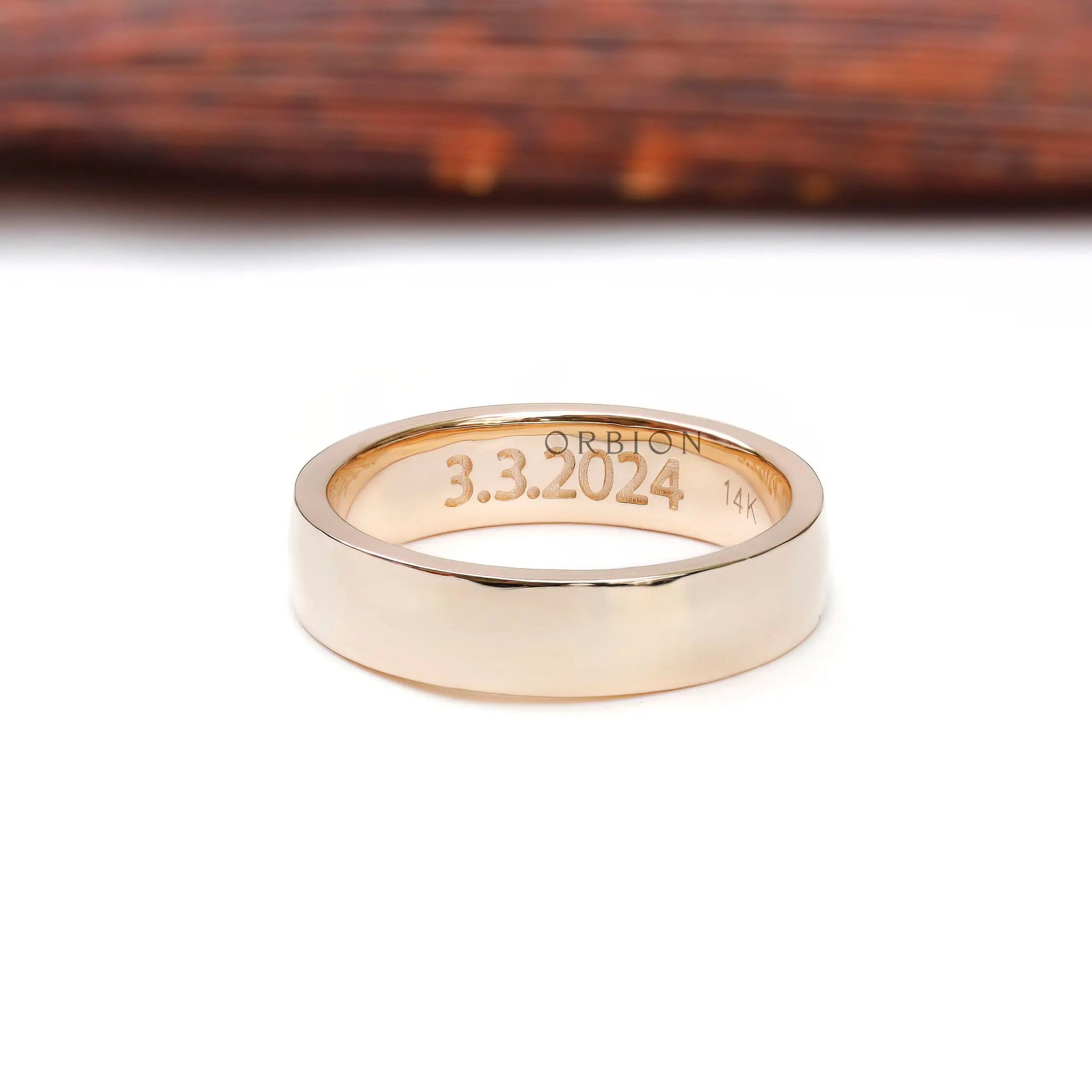 Inside view of wide gold wedding band showing date engraving and gold hallmark.