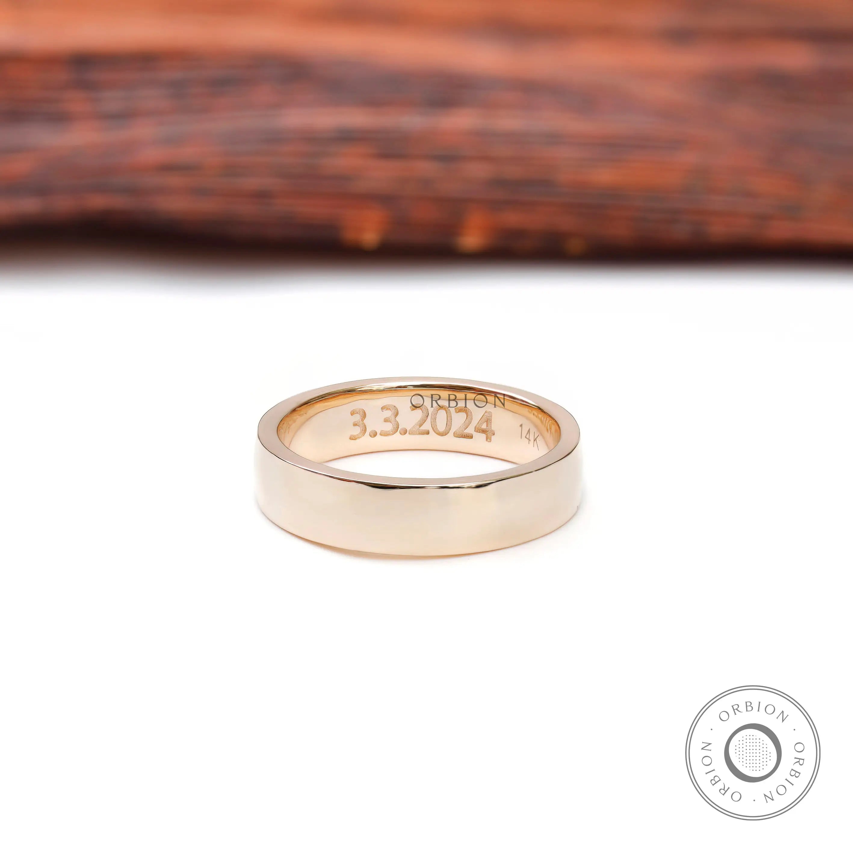 Inside view of wide gold wedding band showing date engraving and gold hallmark.