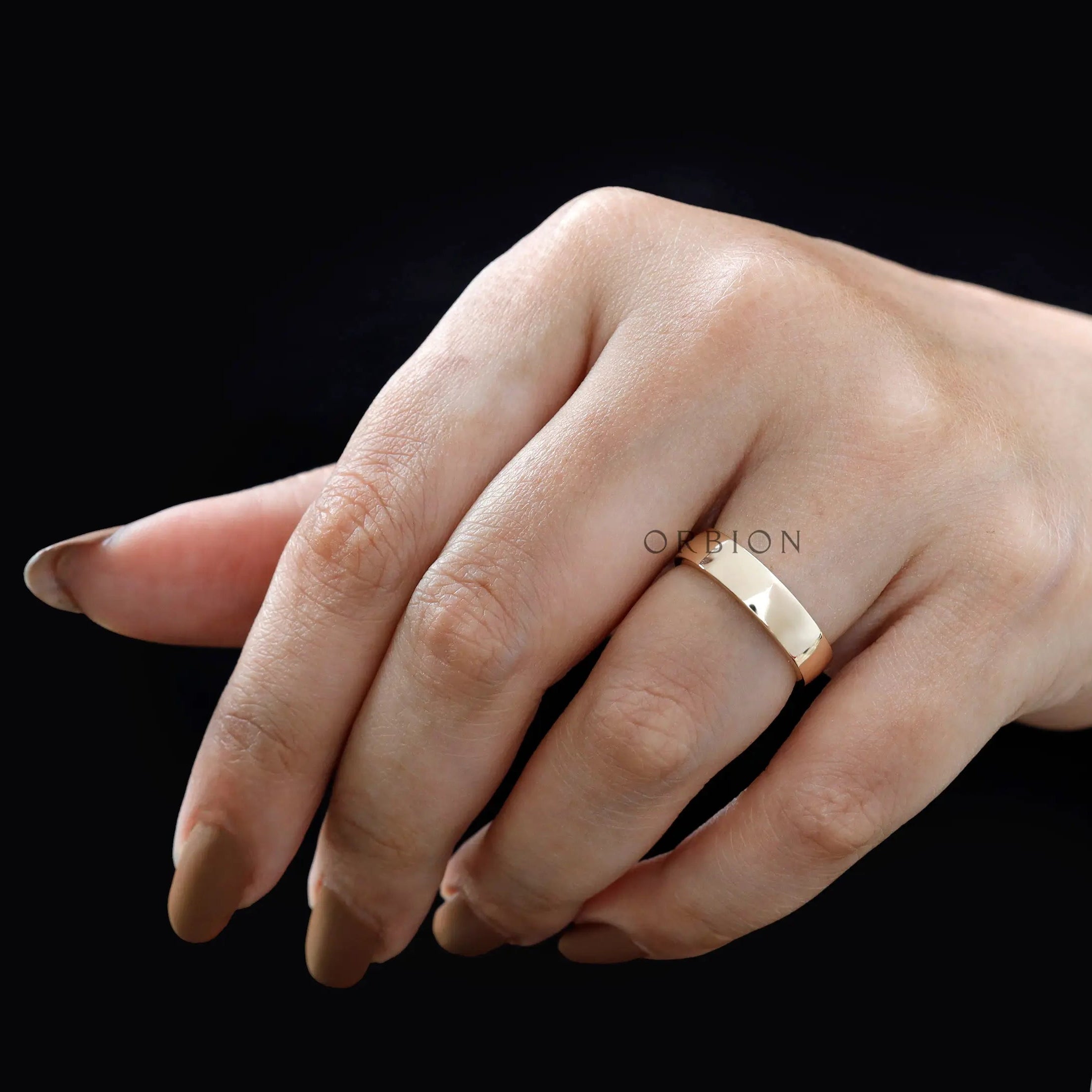 Plain yellow gold wedding band worn on hand with a clean minimalist look.