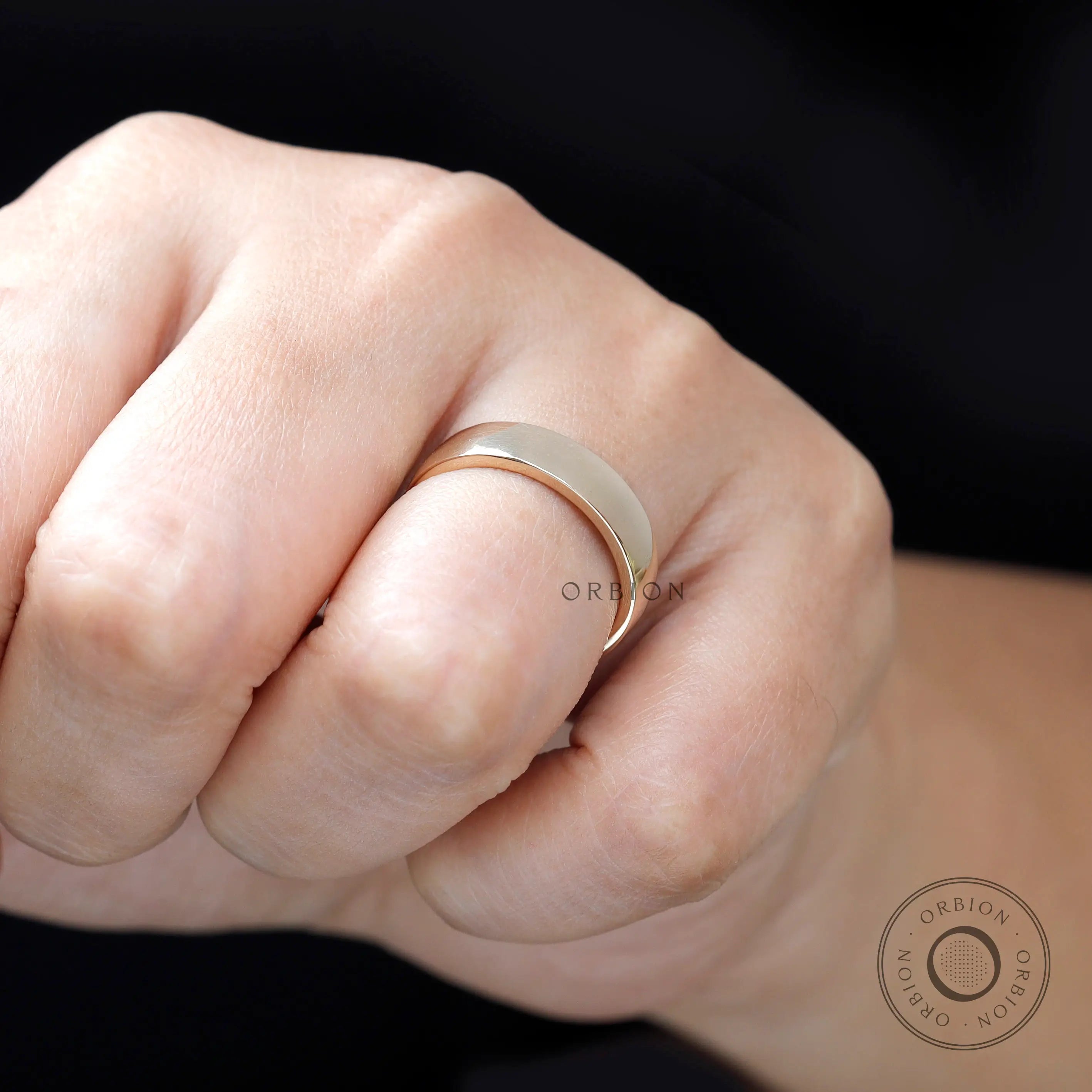 Close-up of yellow gold comfort fit wedding band on finger showing high polish shine.
