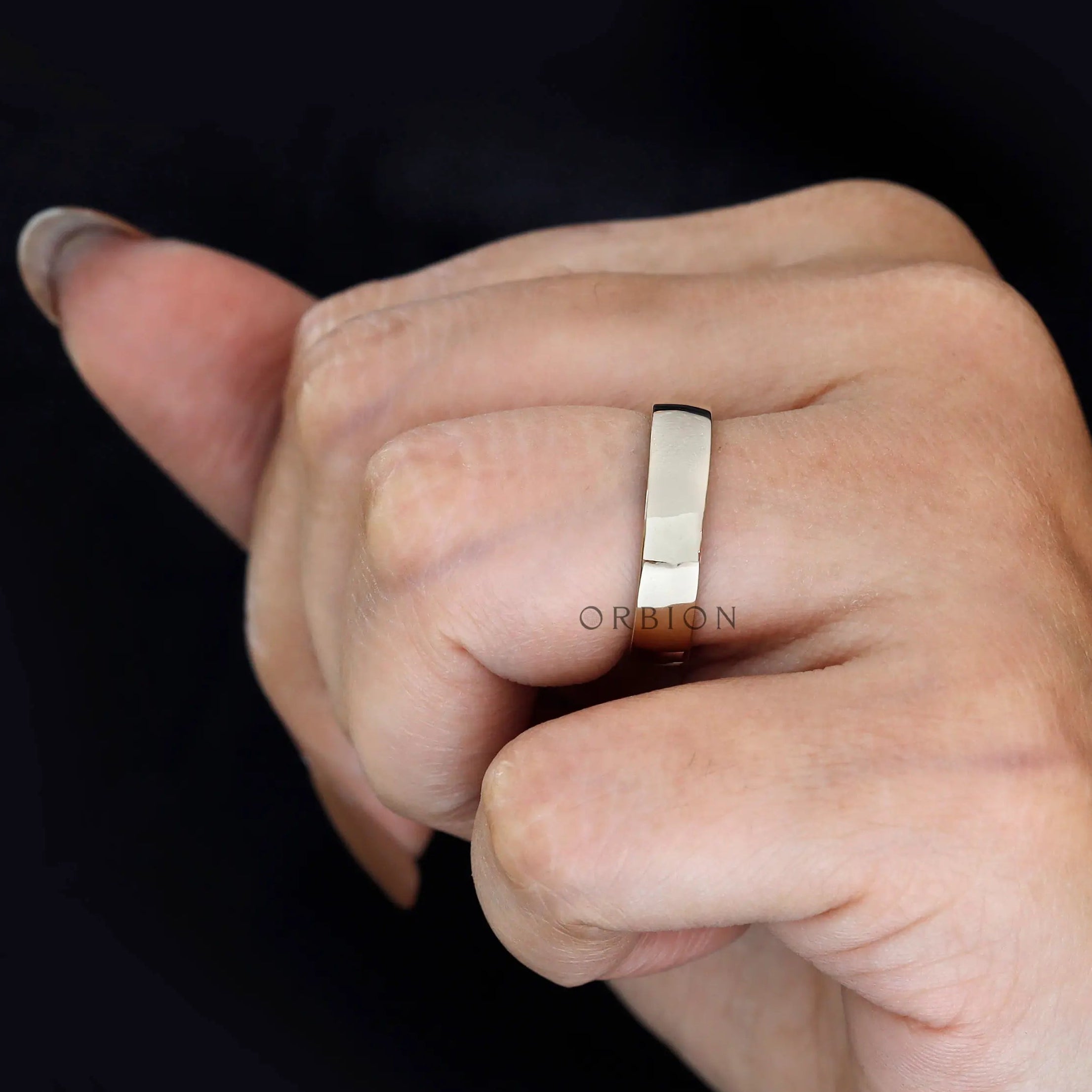 Top view of classic 5mm plain yellow gold wedding band worn on finger.