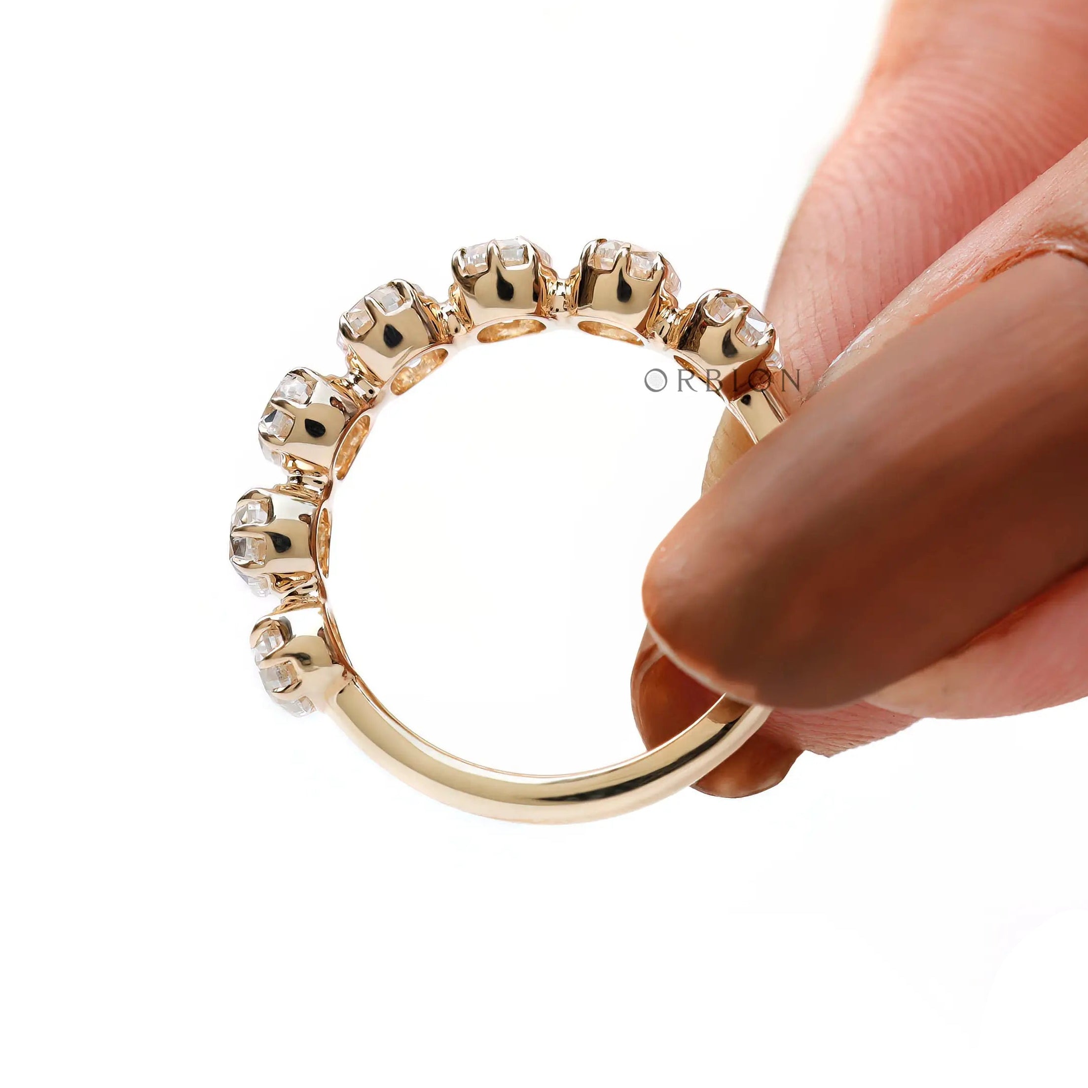 Hand-held close-up of band showing scalloped prongs, and polished yellow gold shank