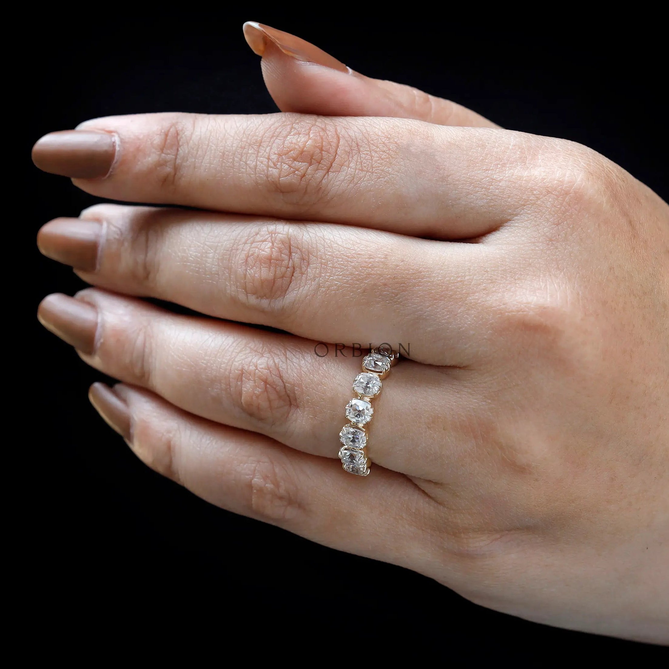 On-hand top view of vintage style  wedding band with bold scalloped prongs
