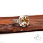 Chunky matte finish three stone ring, angled side view on wood