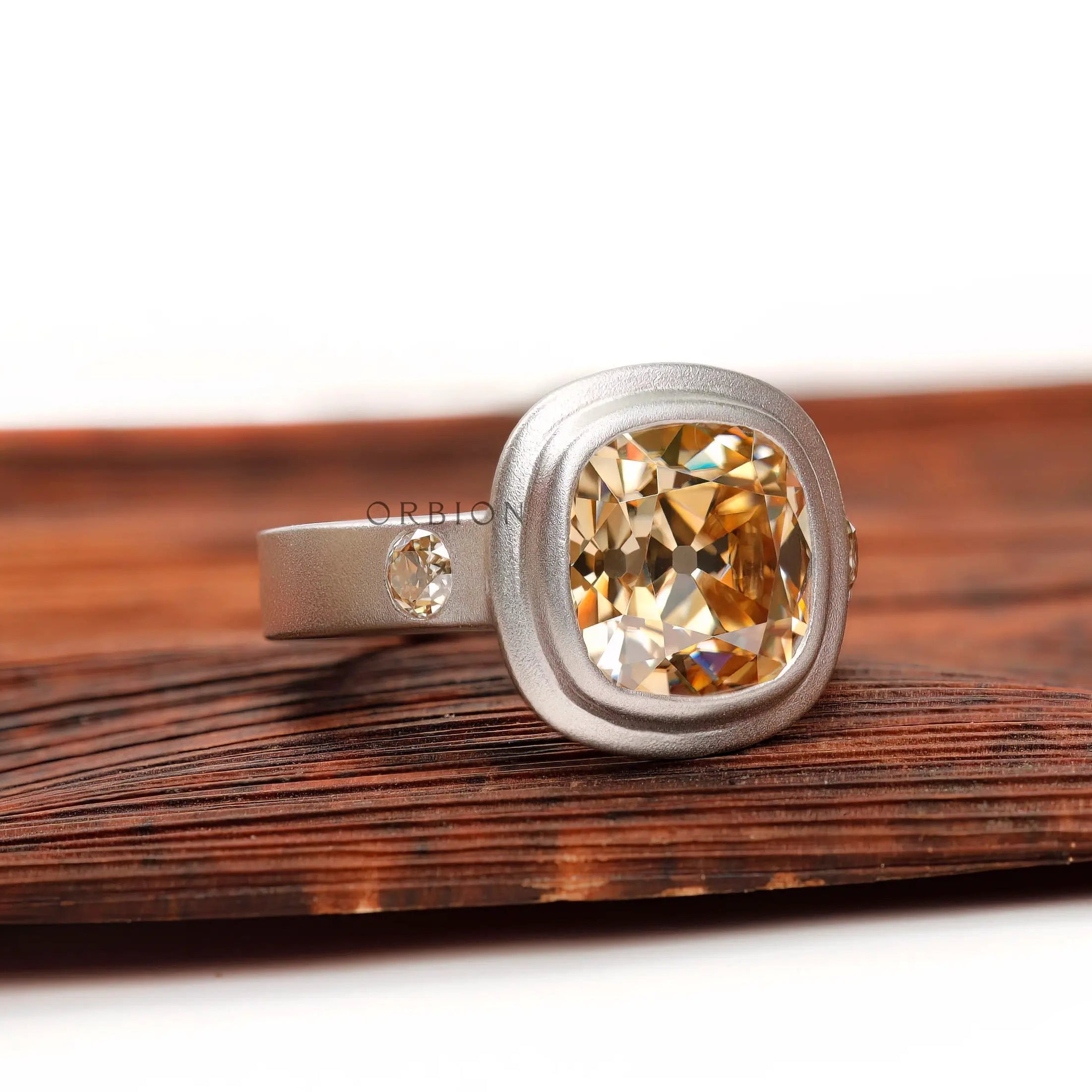 Chunky matte finish three stone ring, angled side view on wood