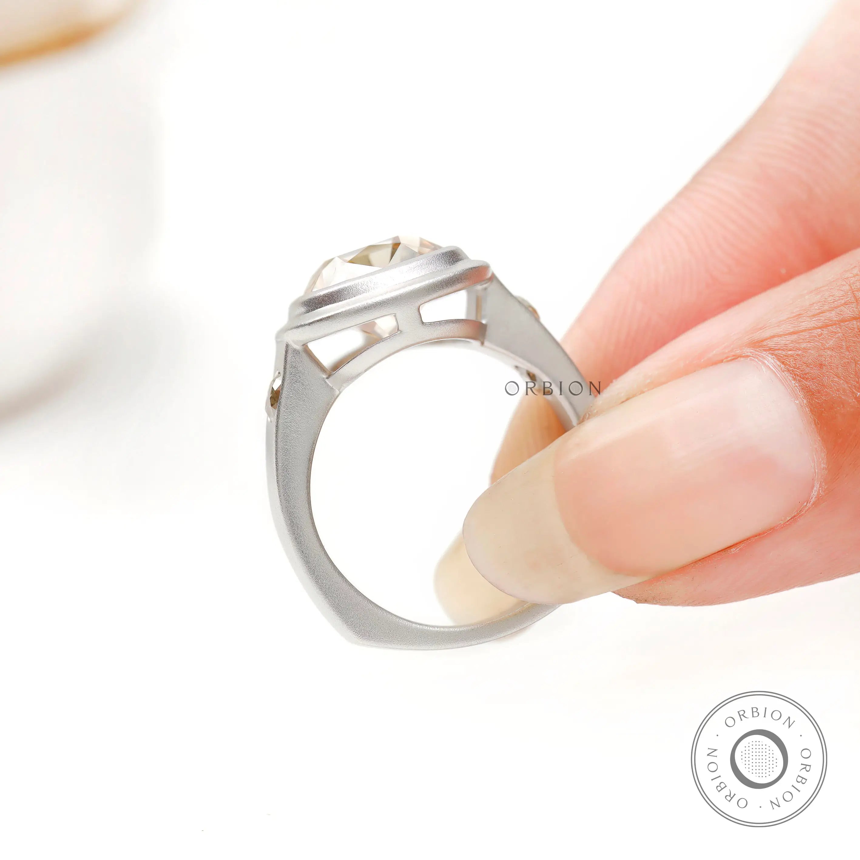 Matte band close up with bezel set side accent stone held on fingers