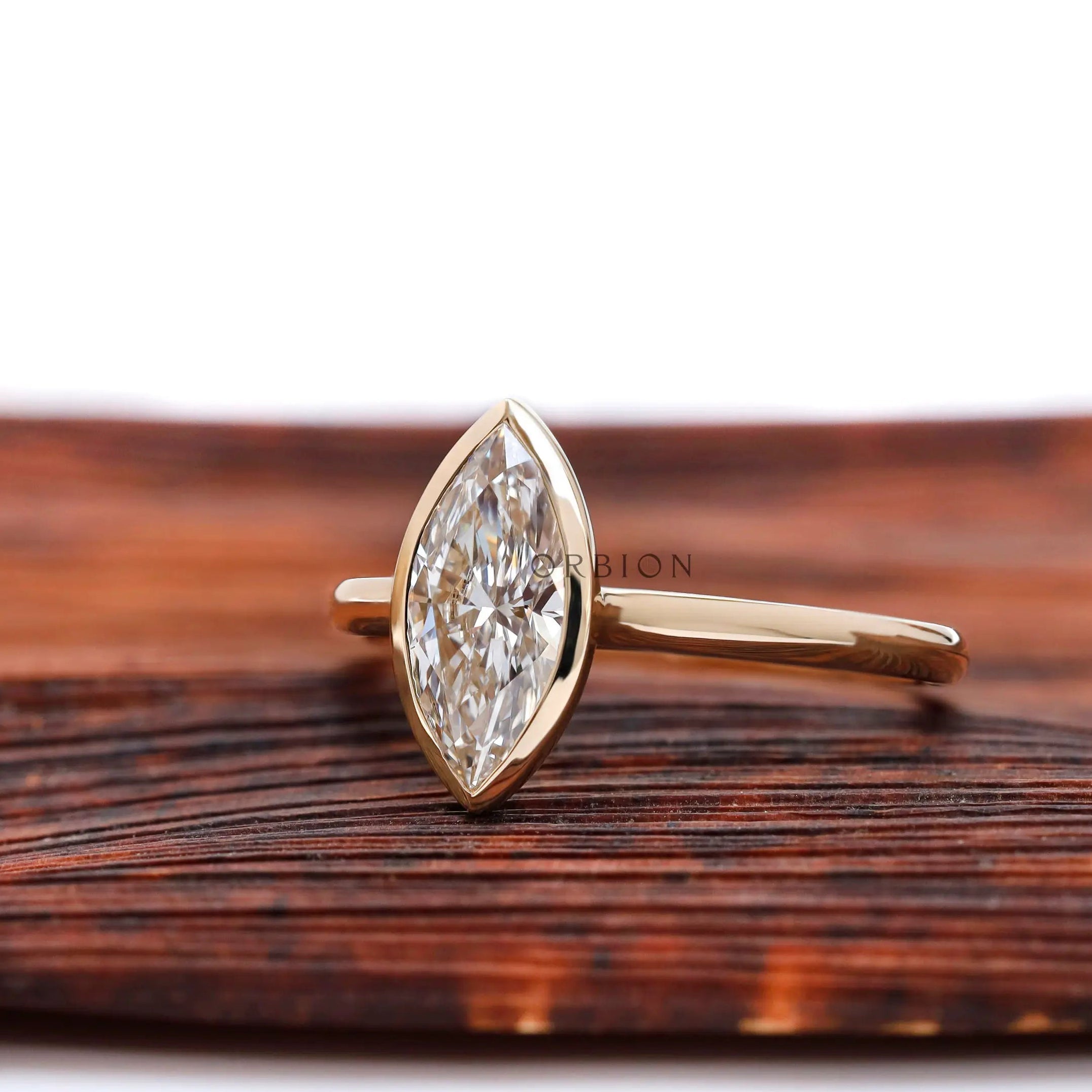 Angled view of marquise bezel solitaire cathedral ring in yellow gold