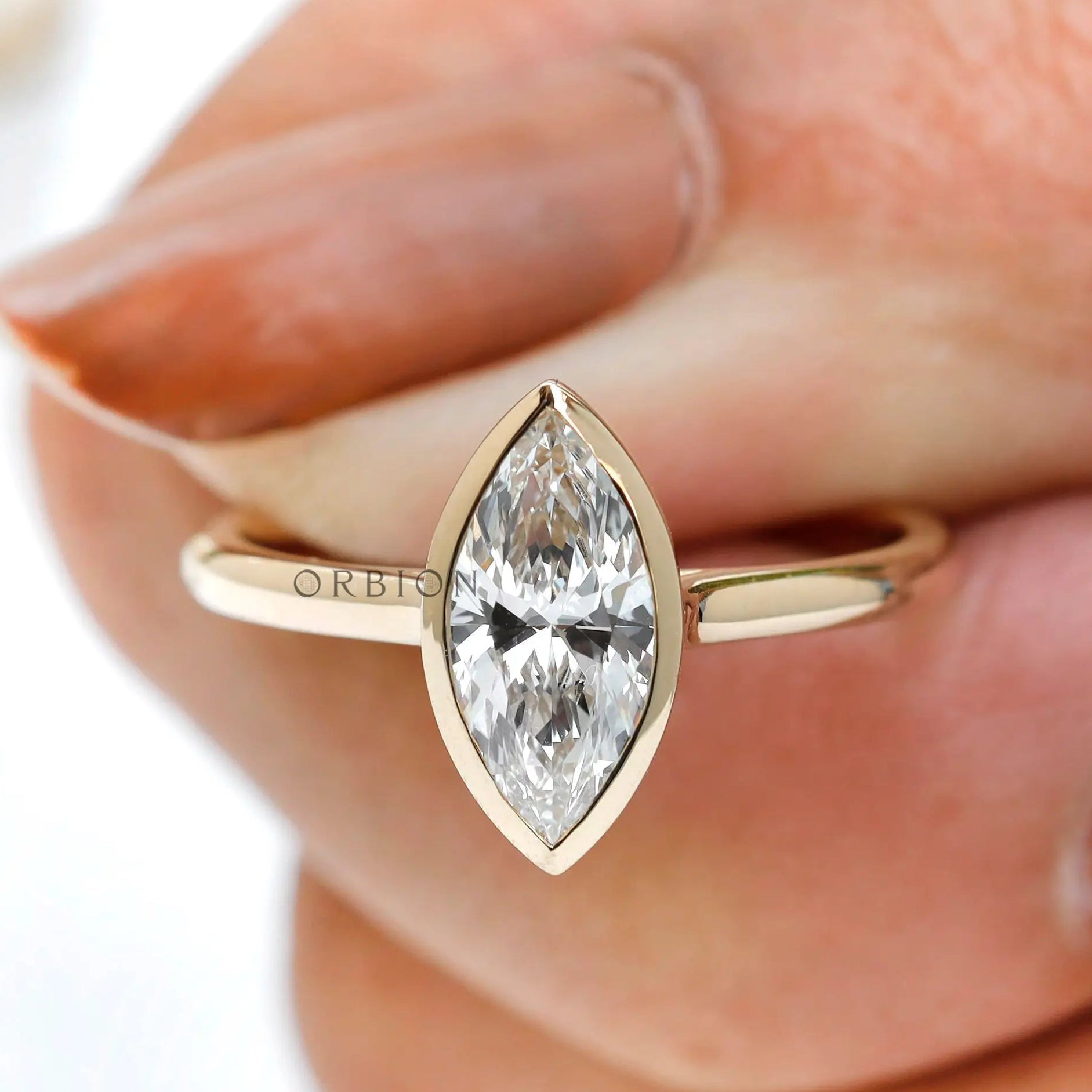 On-hand close-up of marquise bezel solitaire ring in yellow gold