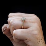 On-hand close view showcasing delicate halo and slim yellow gold band.