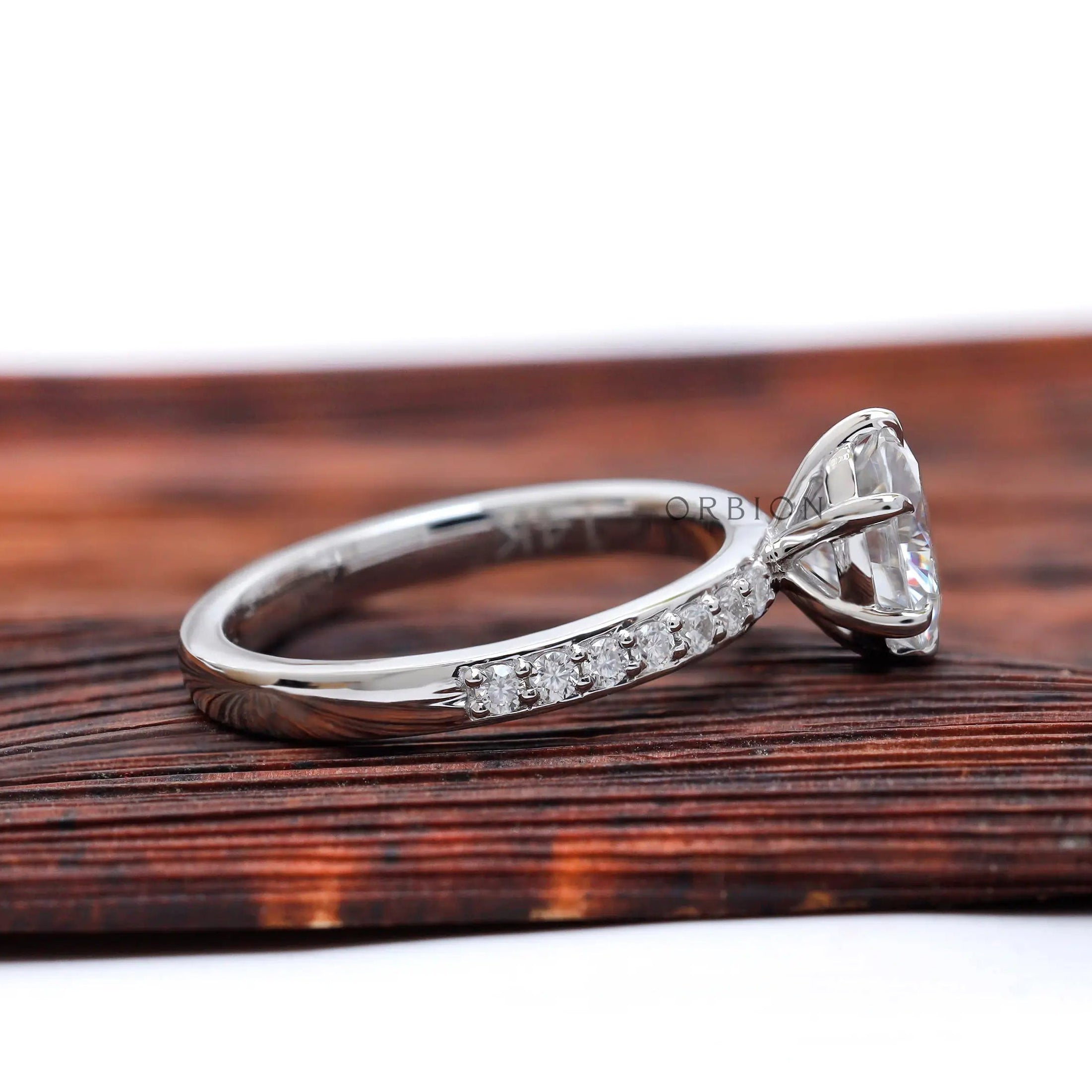 Side profile showing six-prong basket and pave half-eternity shoulders.