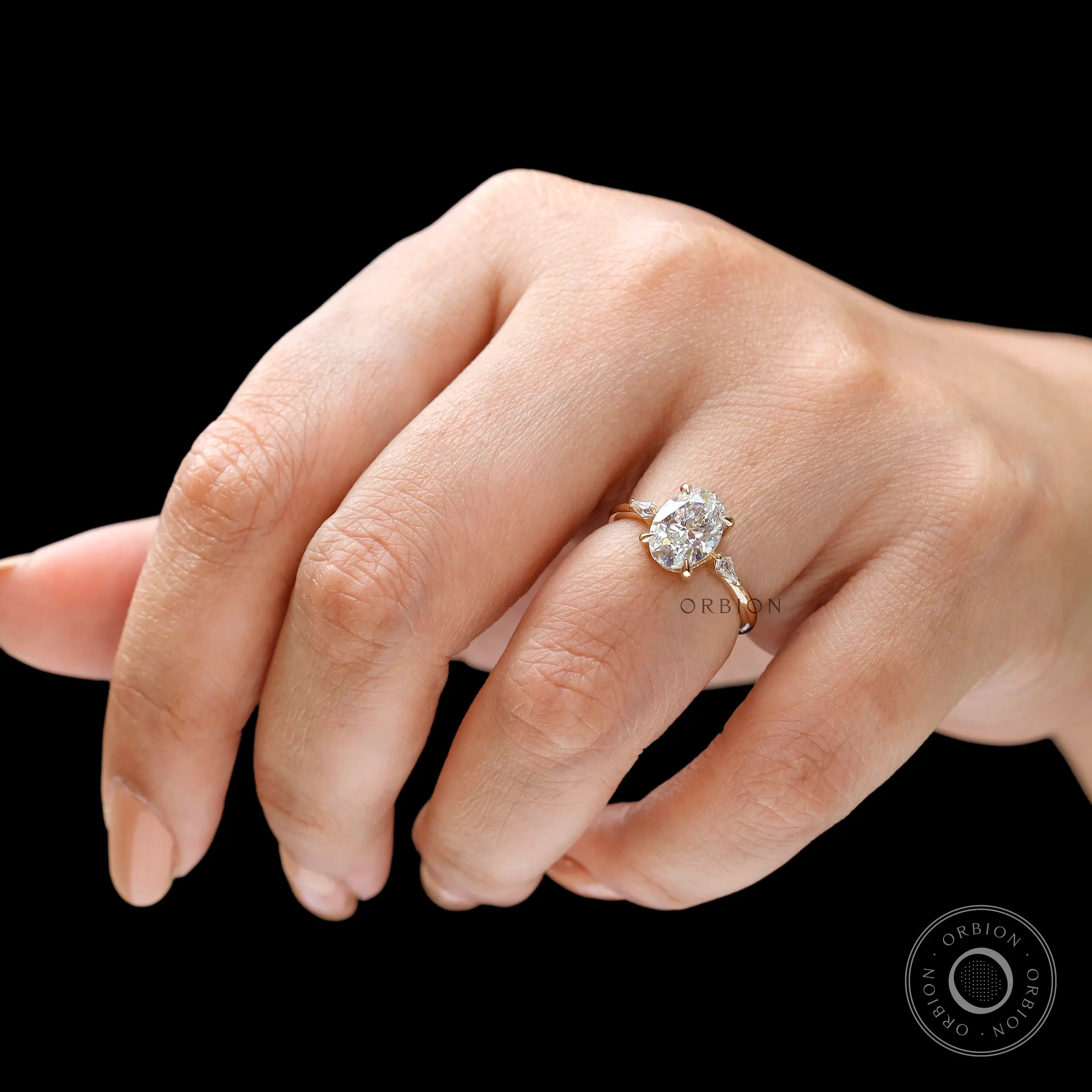 close up of three stone oval engagement ring on hand