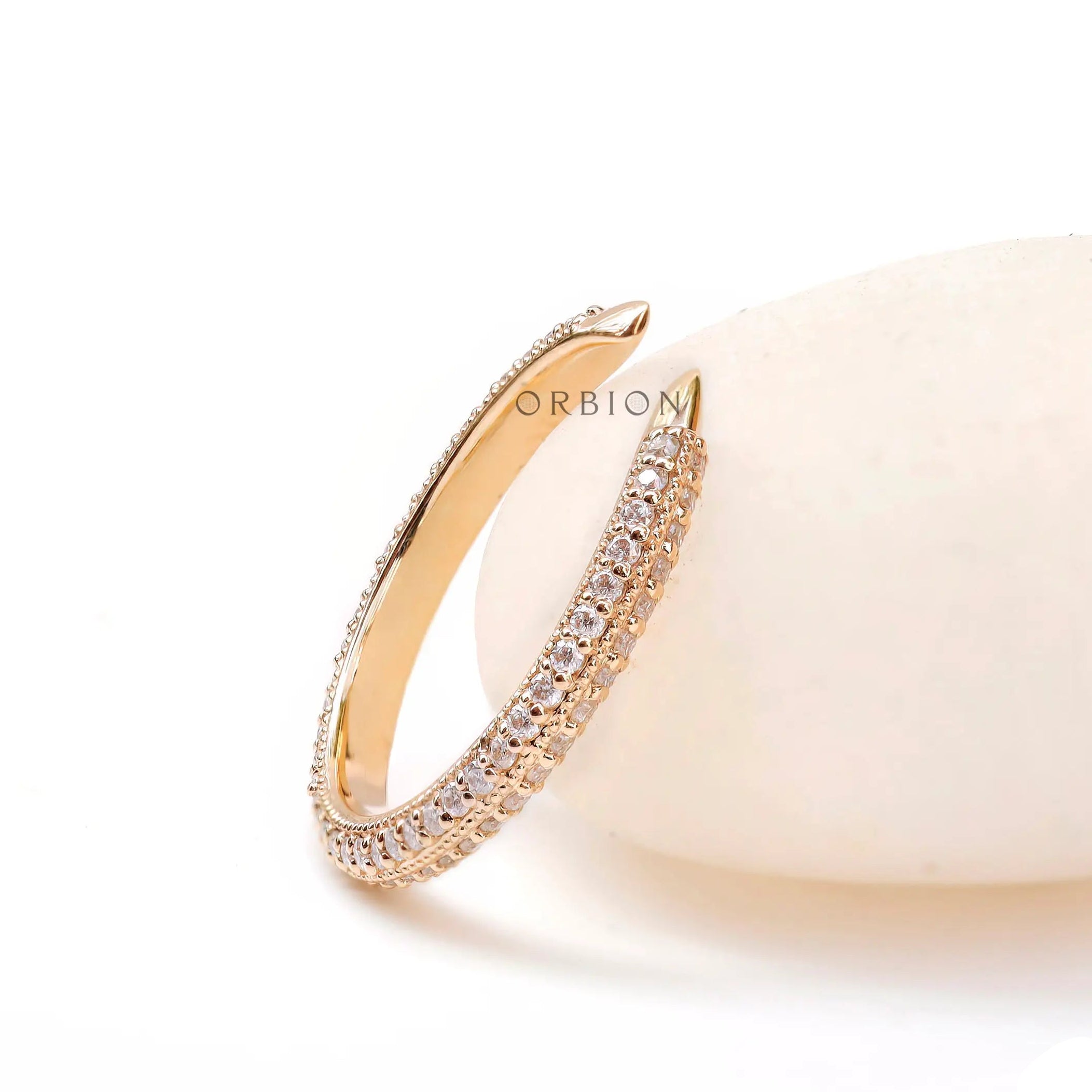 Open spacer pave band resting against soft stone background