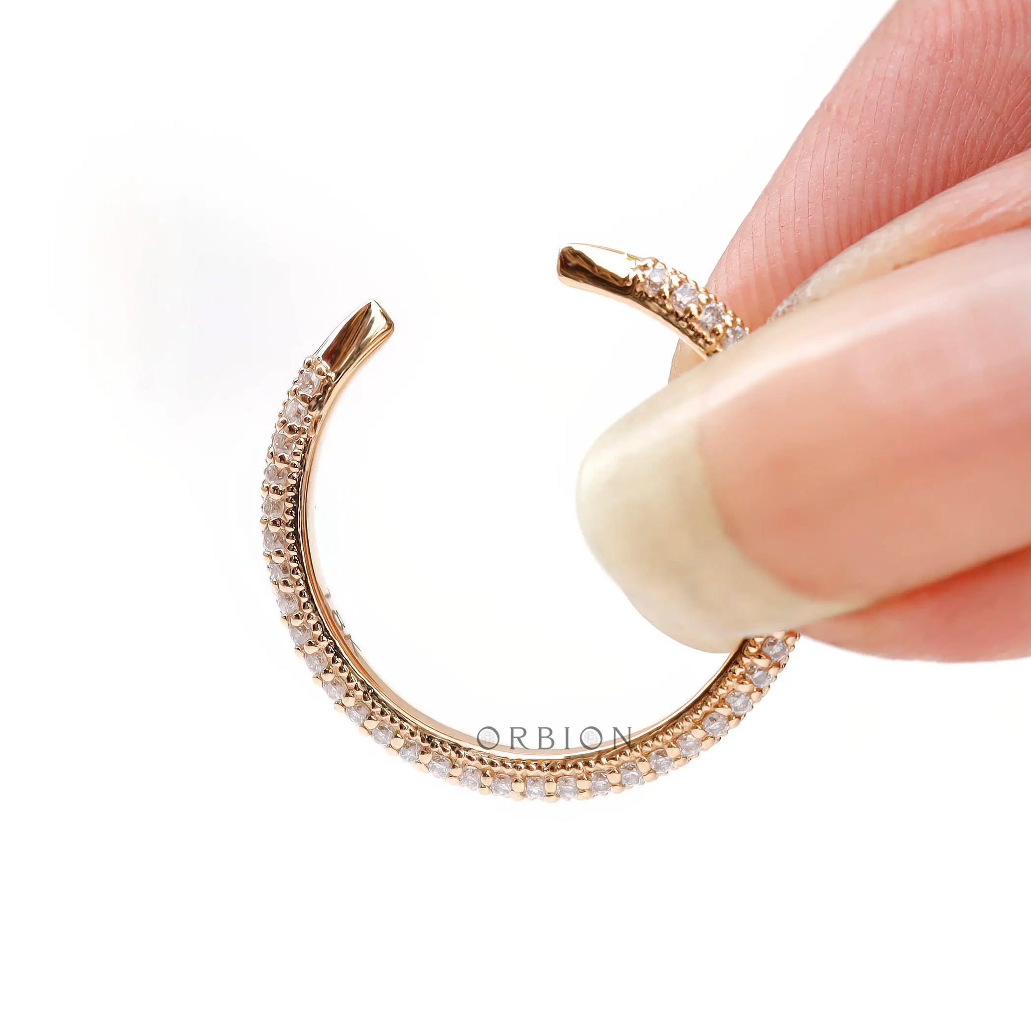 Tiny open claw pave band held between fingers to show delicate scale