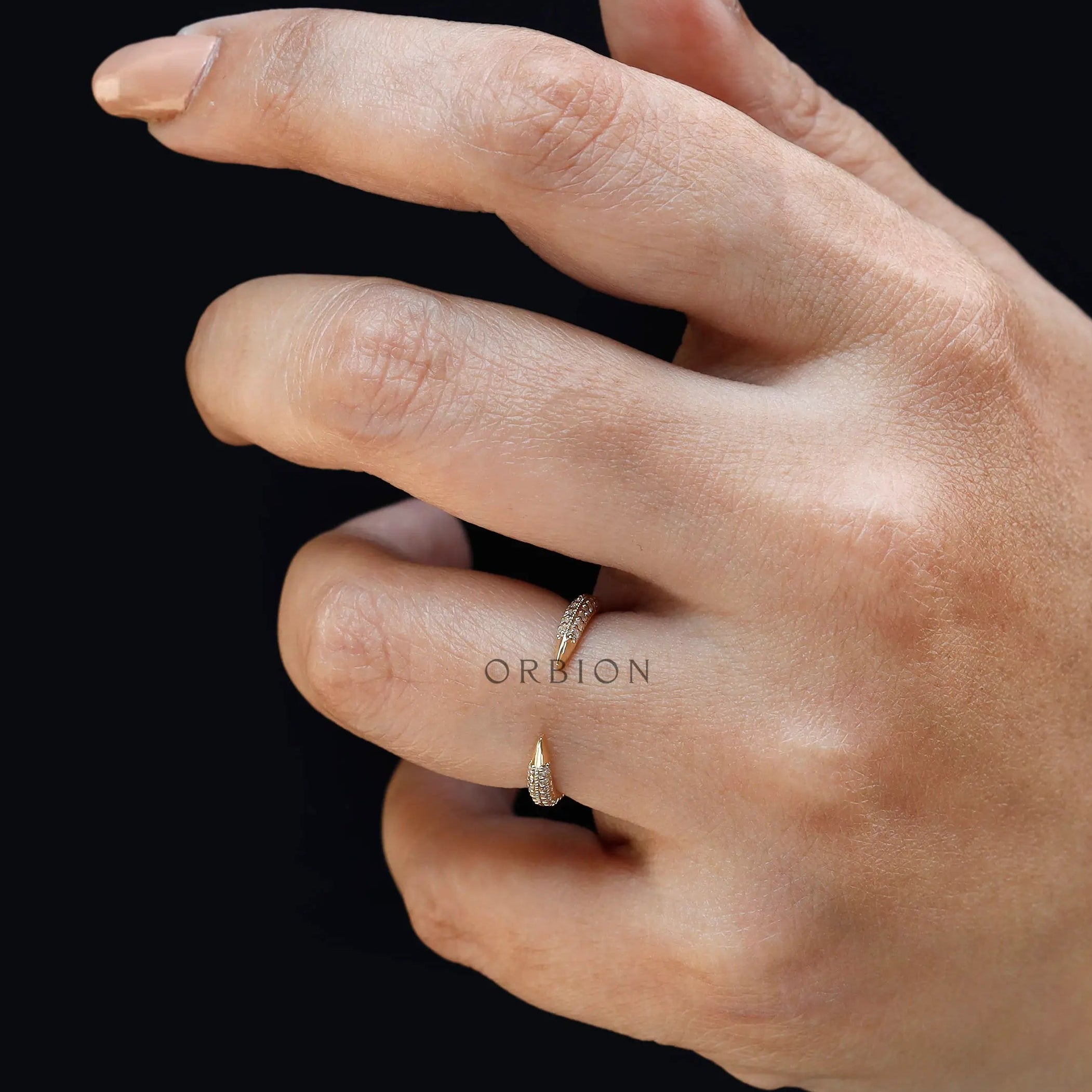 Dainty open claw pave band worn on finger against dark background