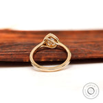 Minimalist pear bezel moissanite ring on wooden surface