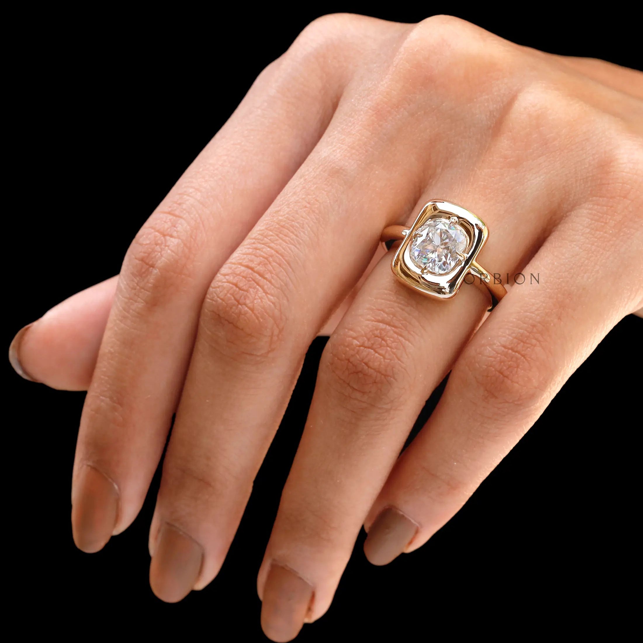 Cushion moissanite bezel ring held in hand