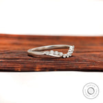 Angled view of curved diamond wedding band showing bubble prong setting