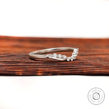 Angled view of curved diamond wedding band showing bubble prong setting