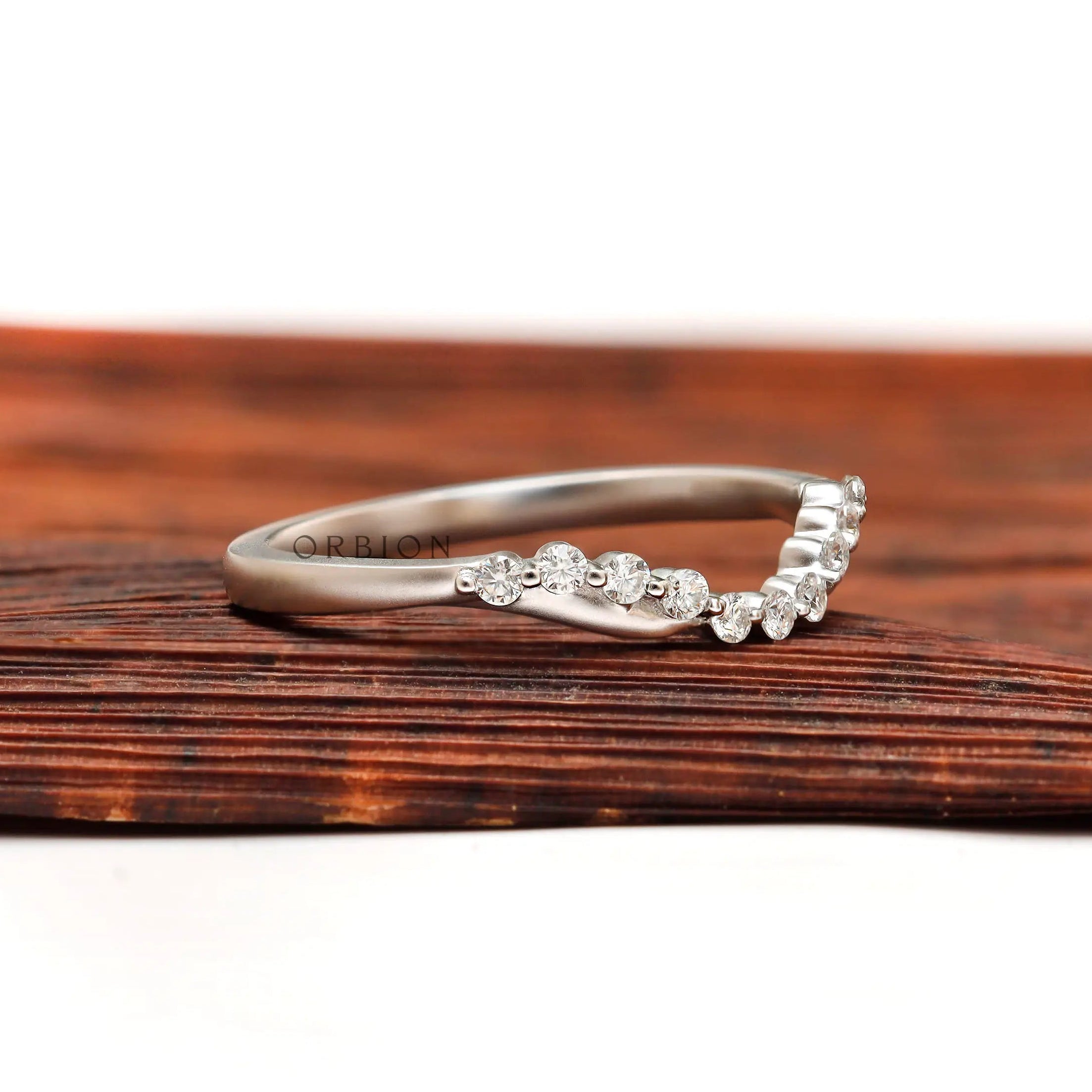Angled view of curved diamond wedding band showing bubble prong setting