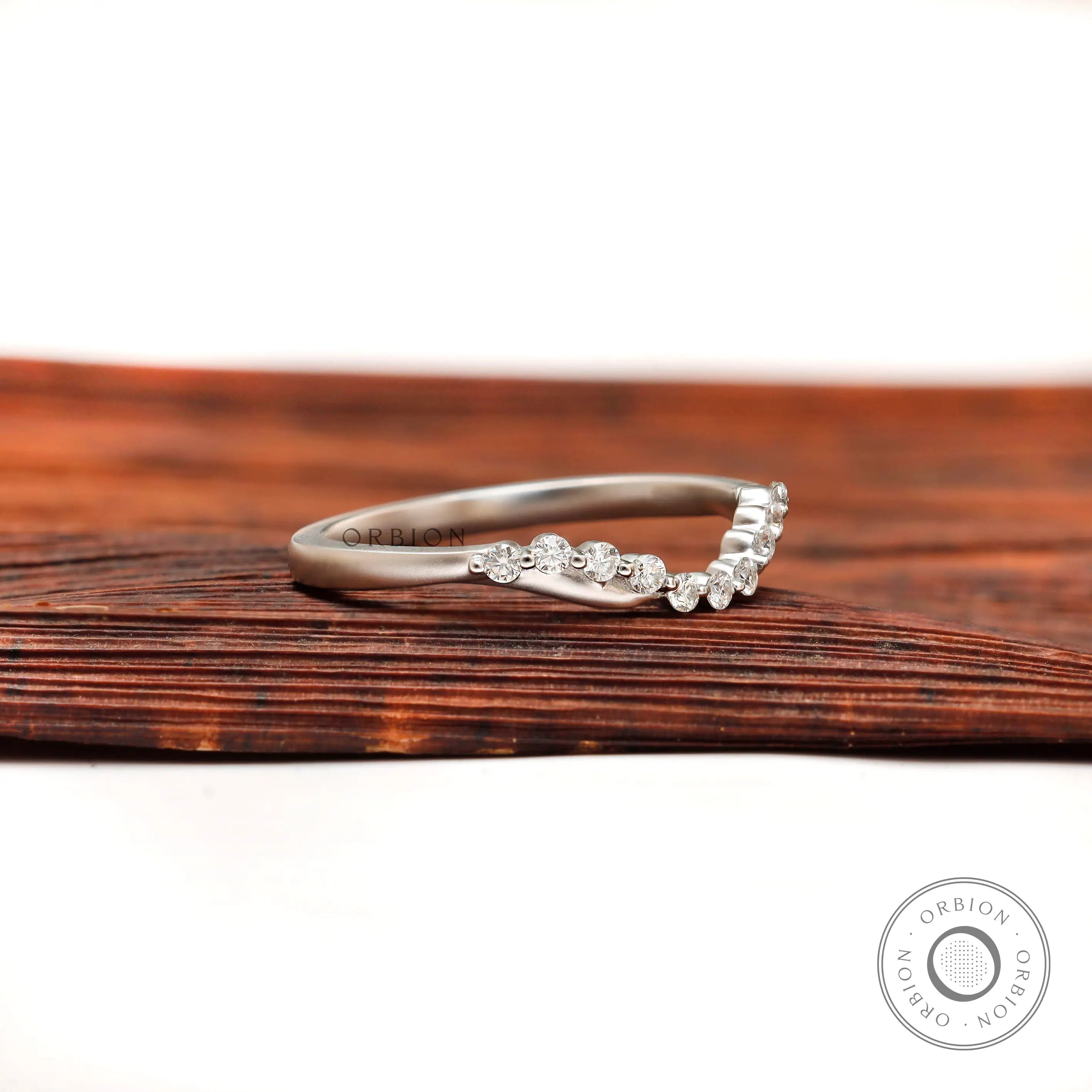 Angled view of curved diamond wedding band showing bubble prong setting