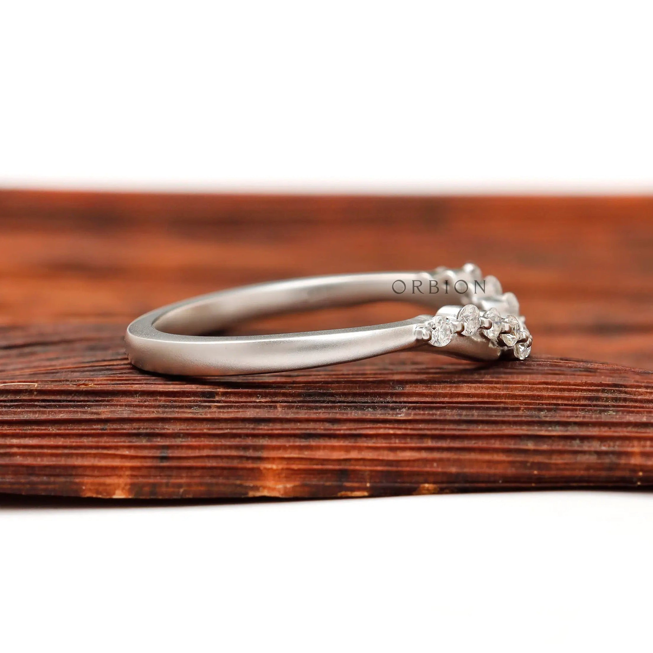 Side profile of matte white gold curved half eternity wedding band