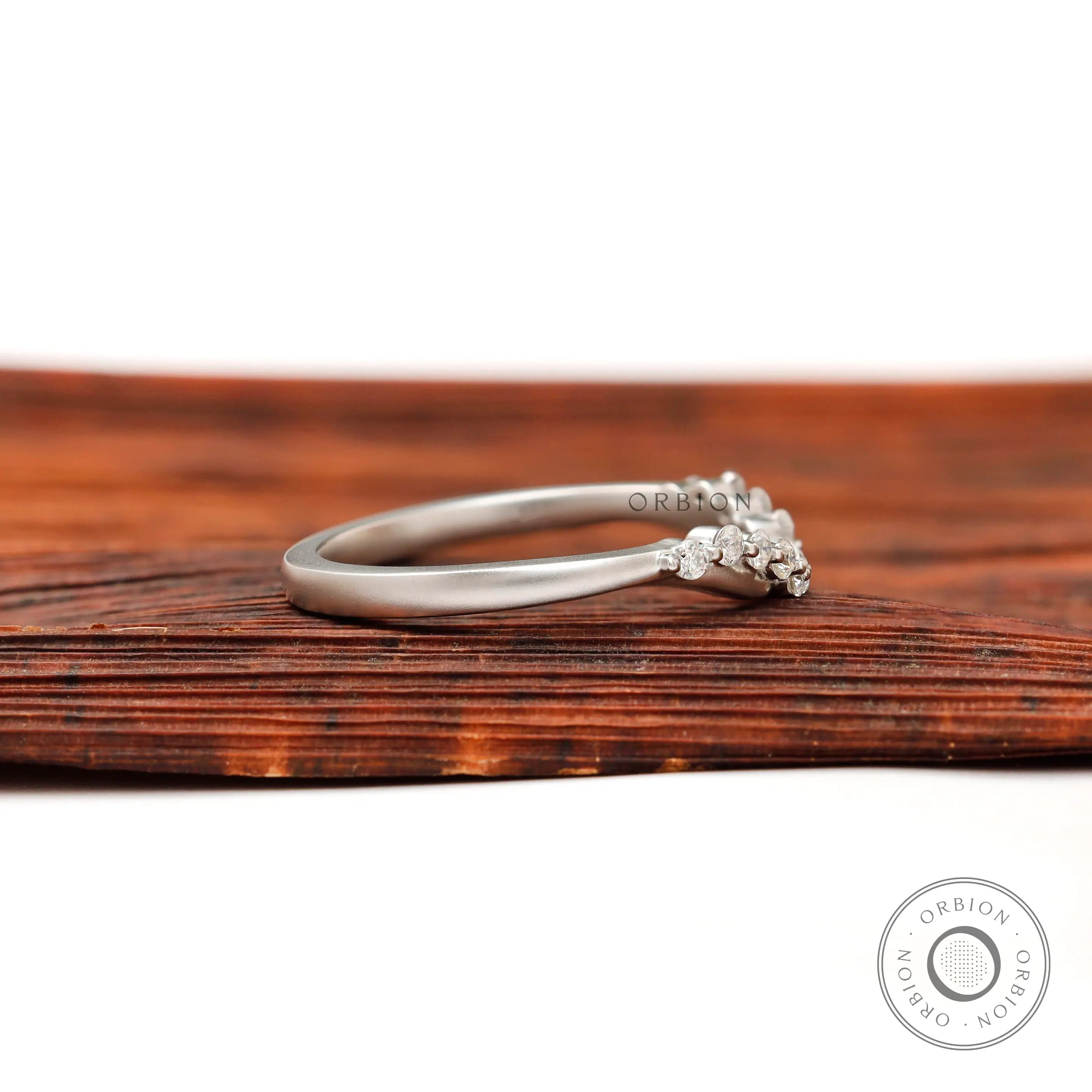 Side profile of matte white gold curved half eternity wedding band