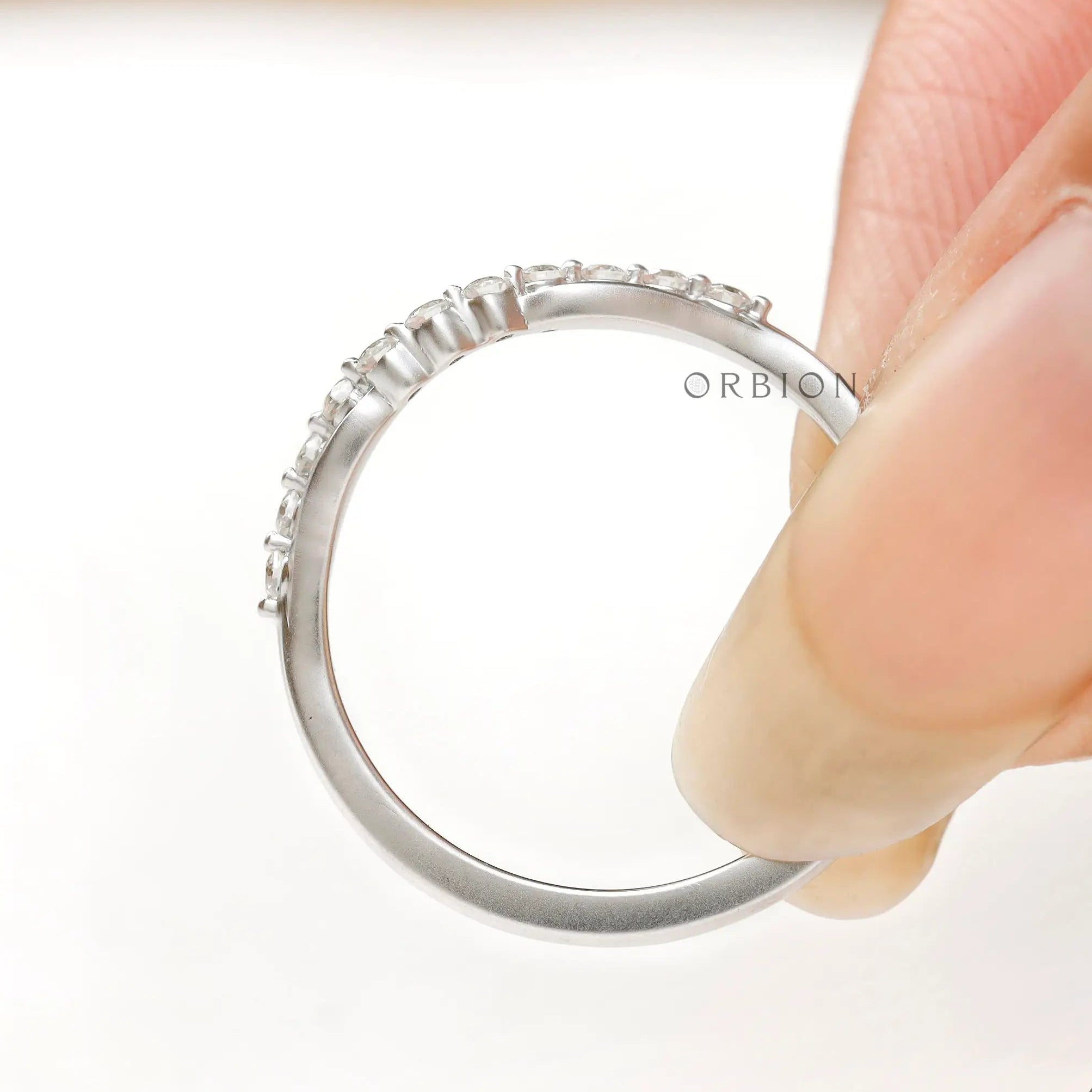 Close-up of bubble prong diamond details on curved wedding band