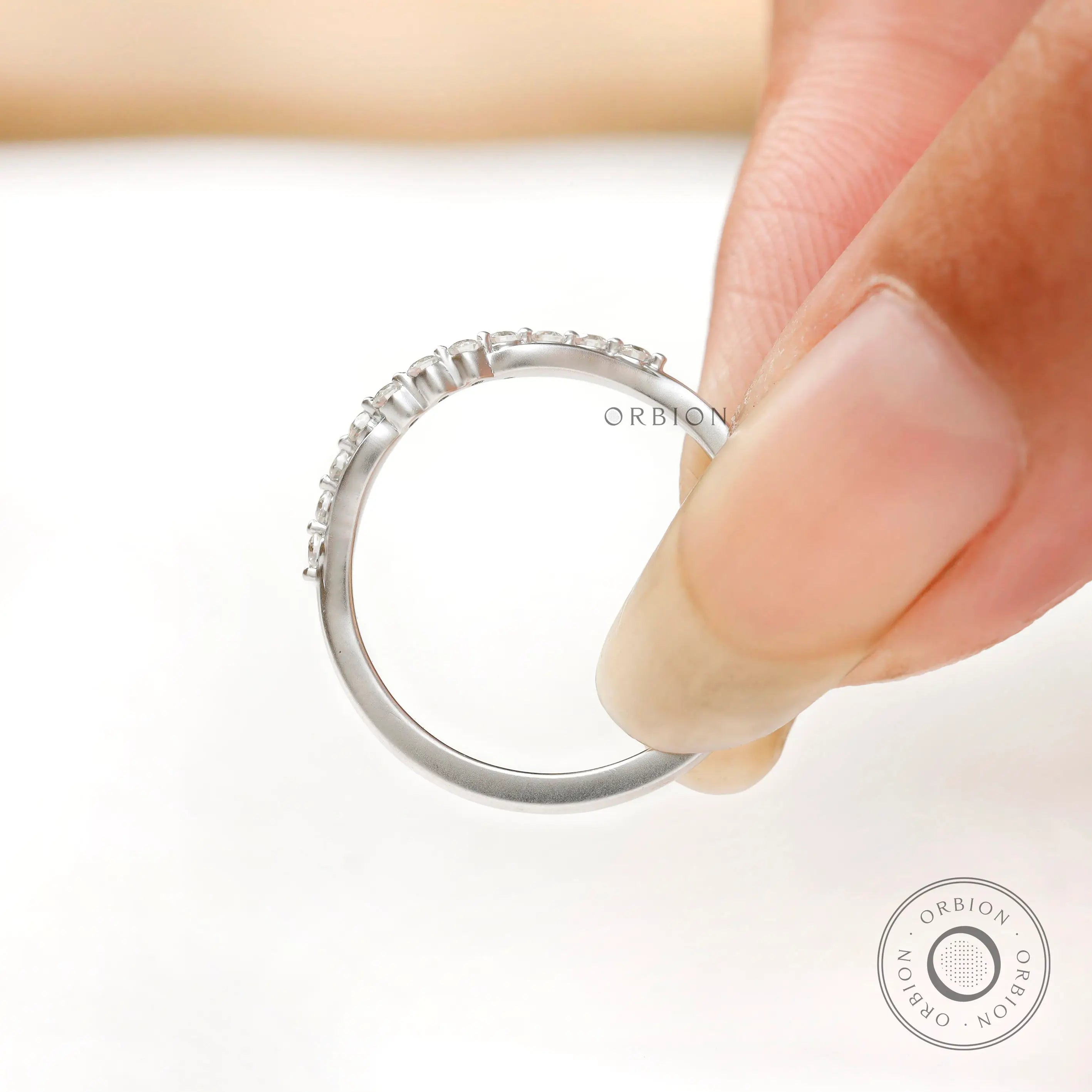 Close-up of bubble prong diamond details on curved wedding band