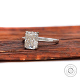 Radiant cut engagement ring resting on wooden surface