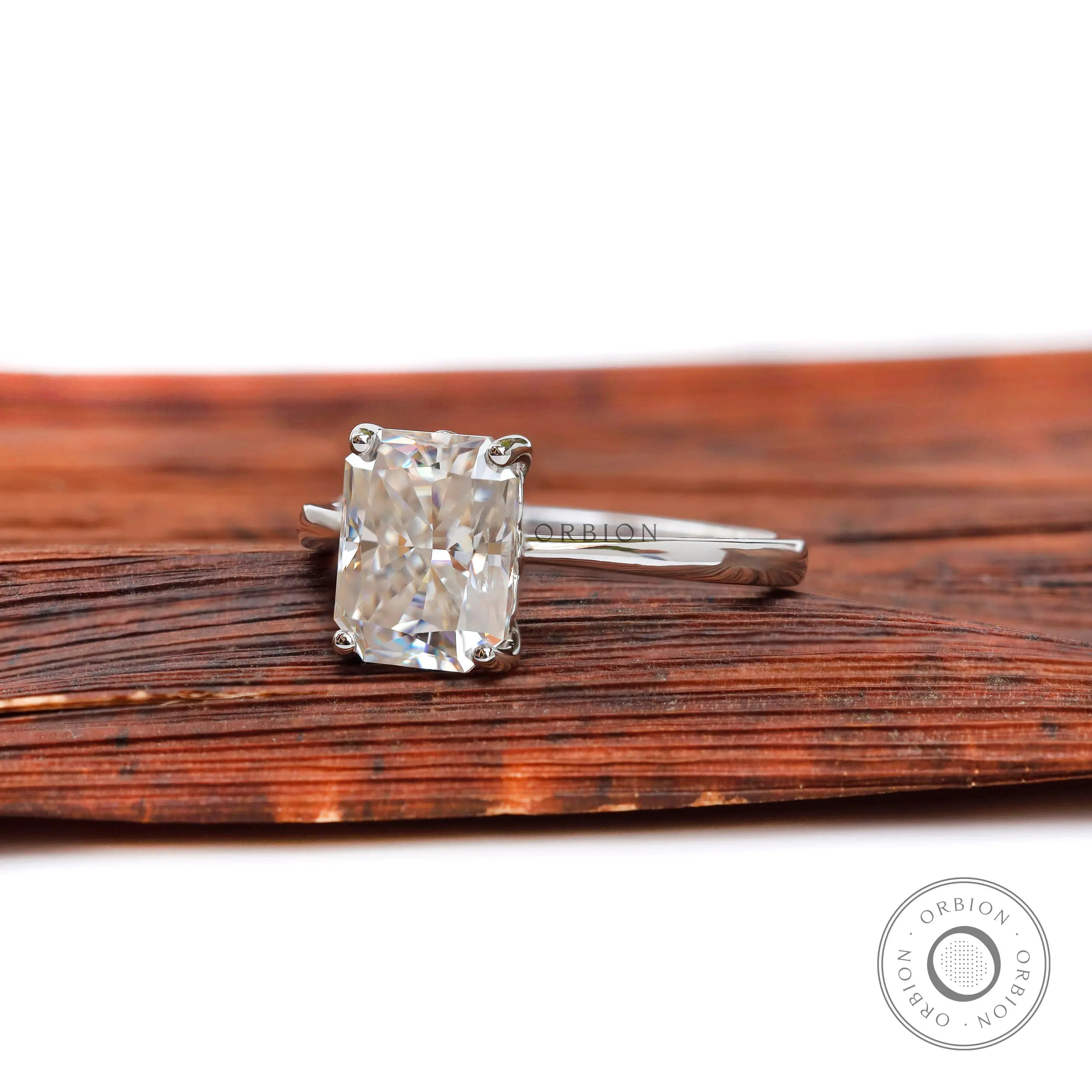 Radiant cut engagement ring resting on wooden surface
