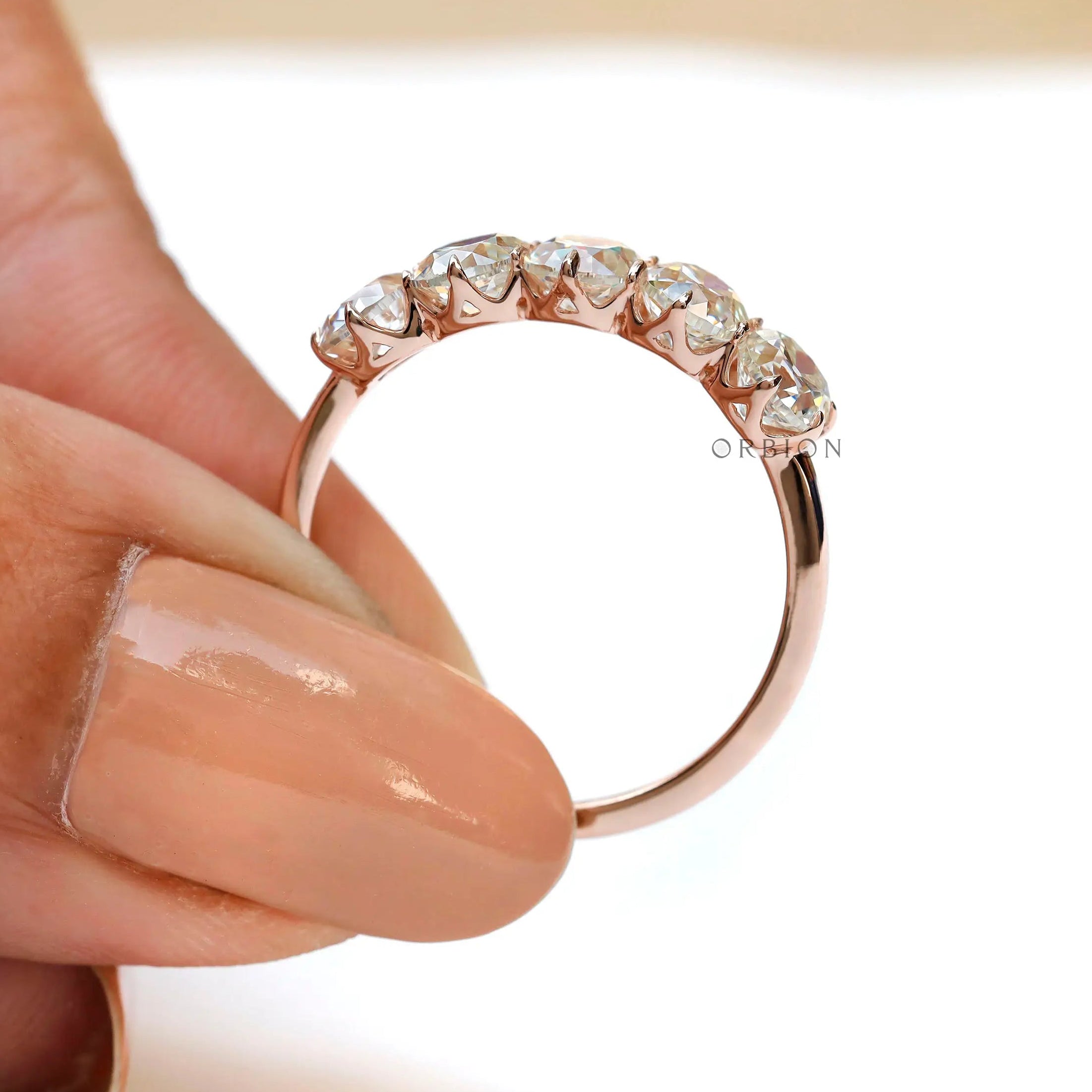 Elongated cushion moissanite band held between fingers