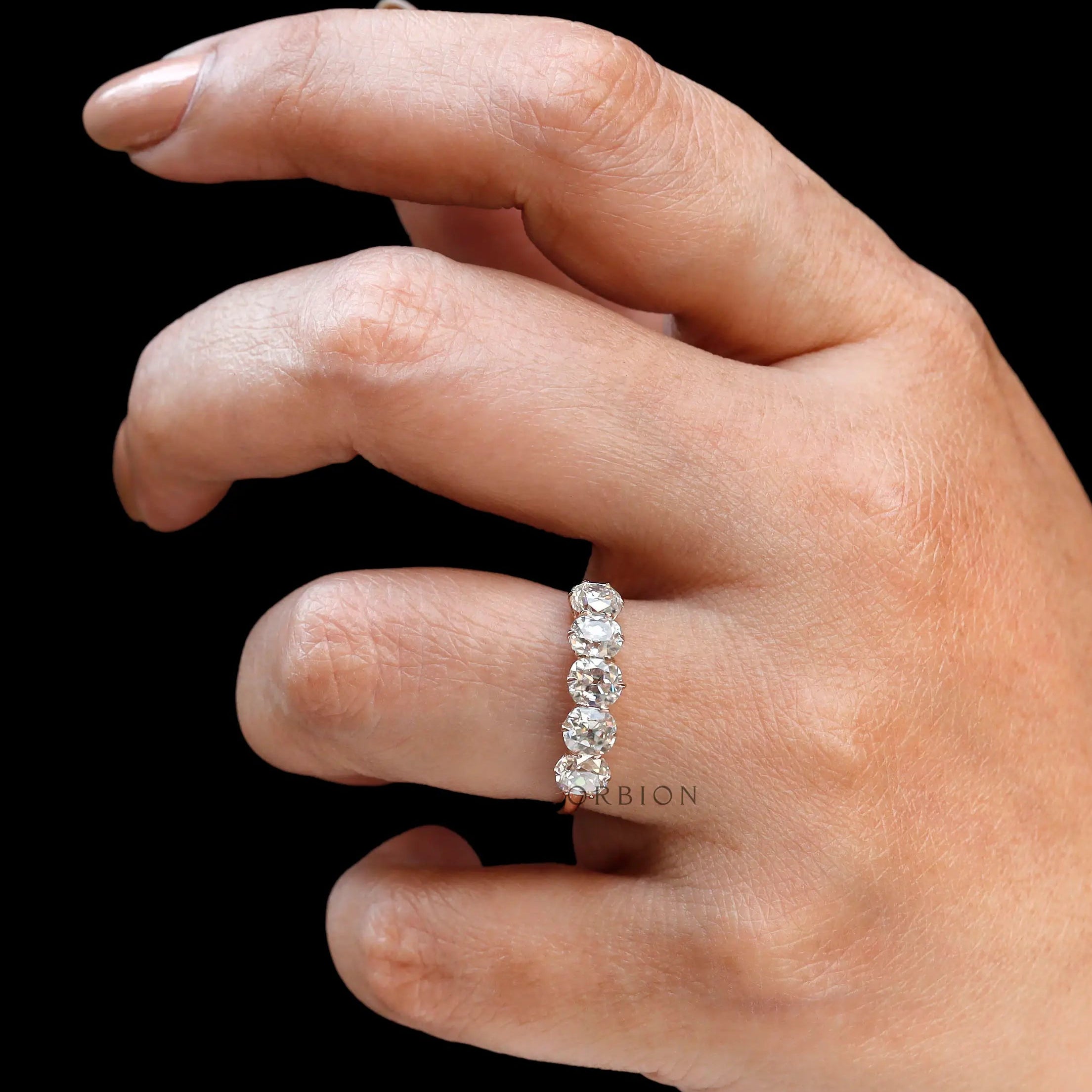Hand close-up showing five elongated cushion moissanites sparkle