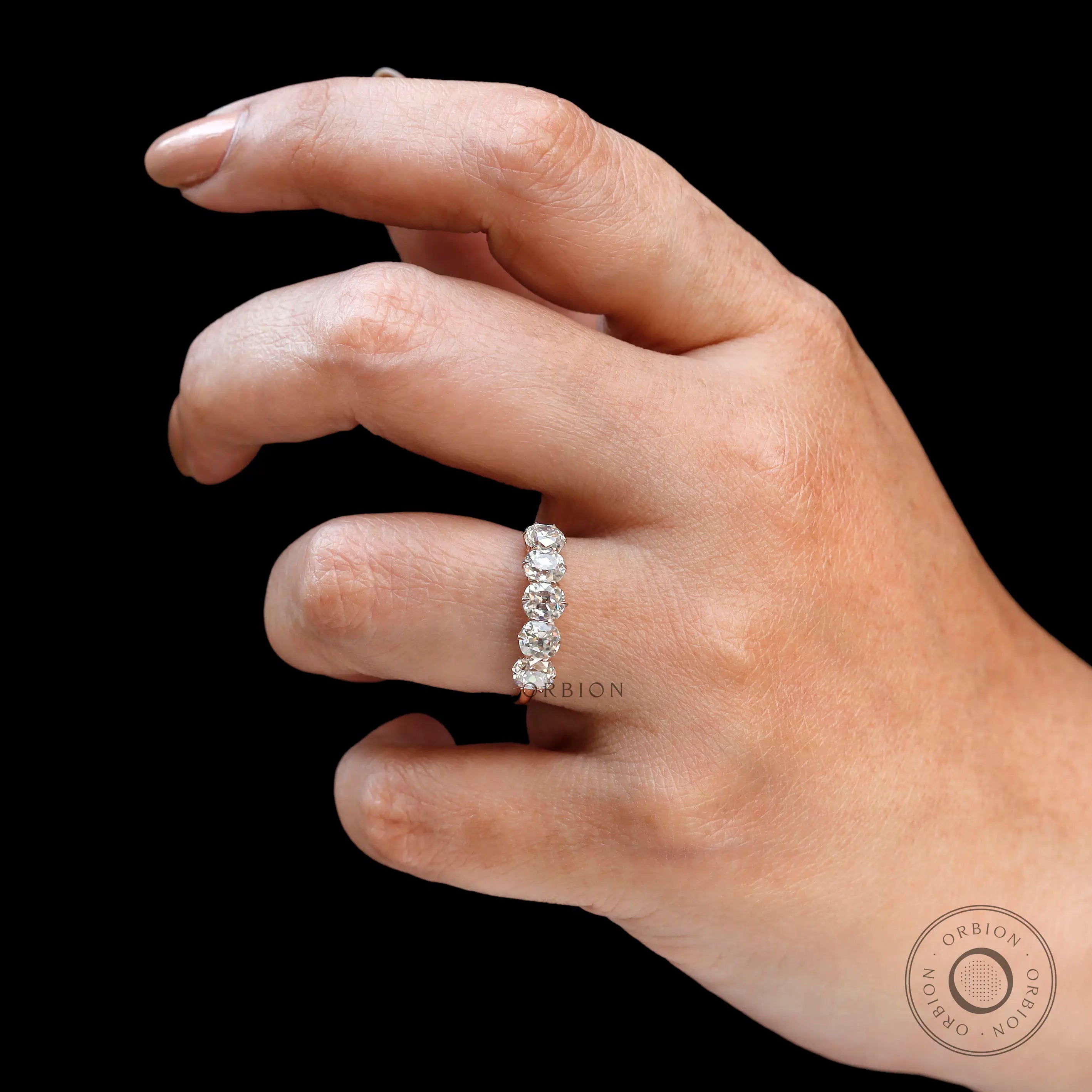 Hand close-up showing five elongated cushion moissanites sparkle