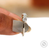 Side view on finger showing low-set bezels and clean silhouette.