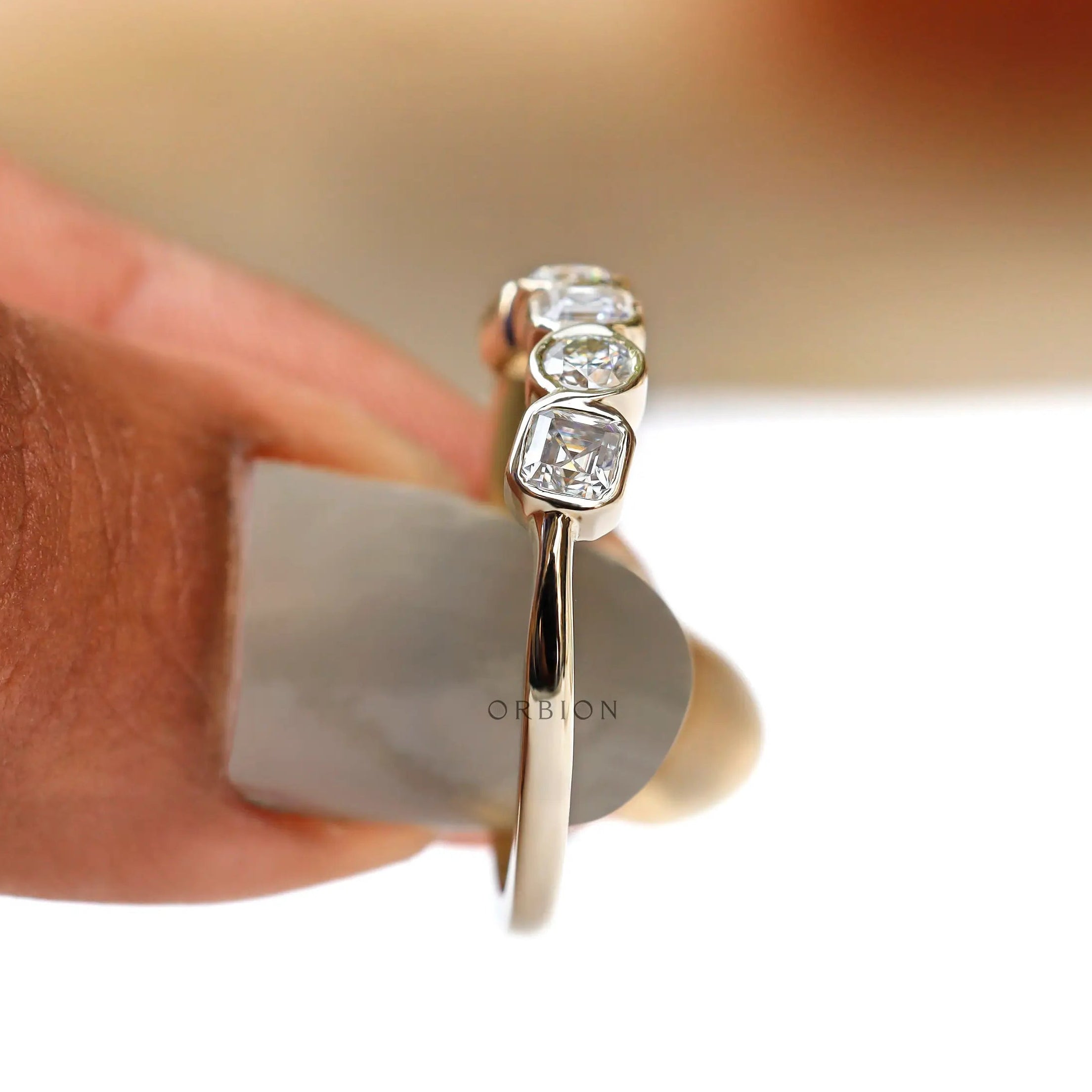 Side view on finger showing low-set bezels and clean silhouette.