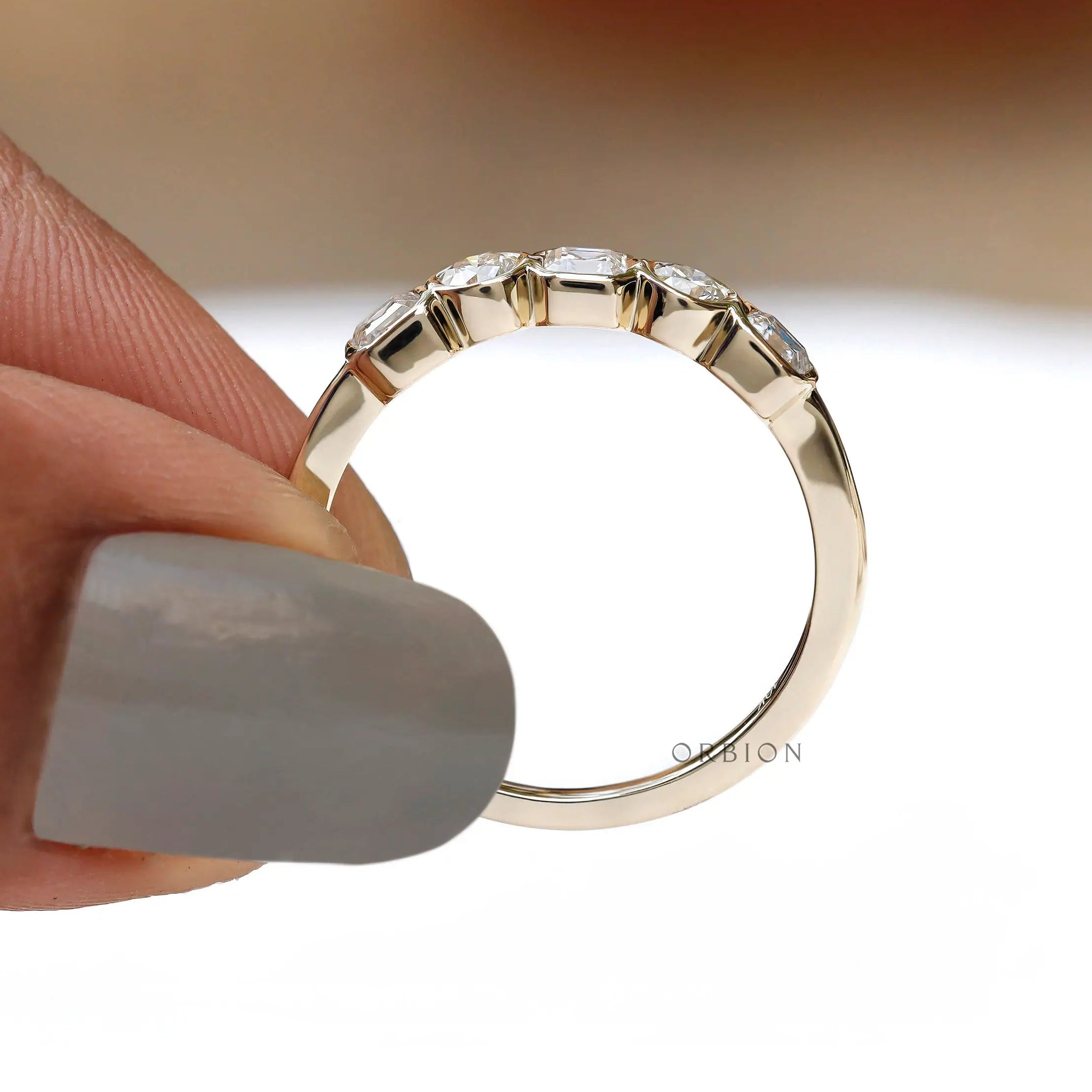 Profile on hand showing tapered band and sparkling five-stone line.