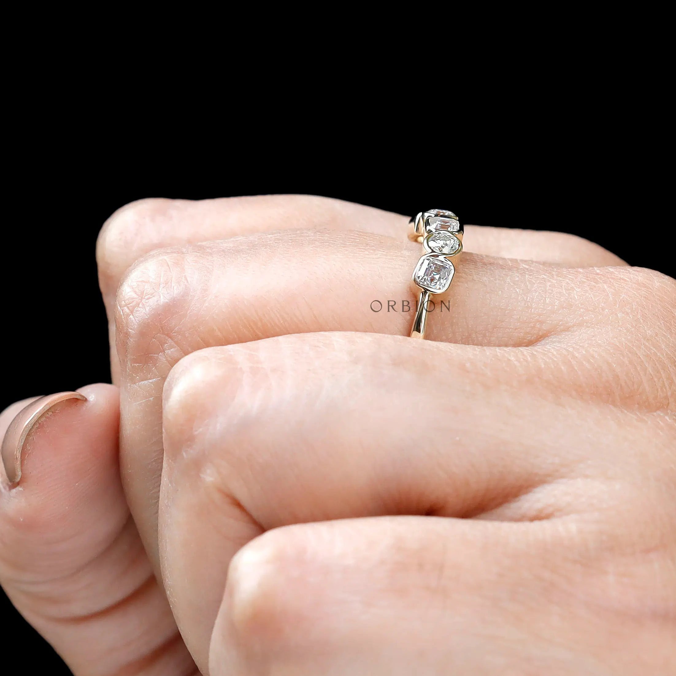 Top view on hand showing five-stone alternating moissanite design.