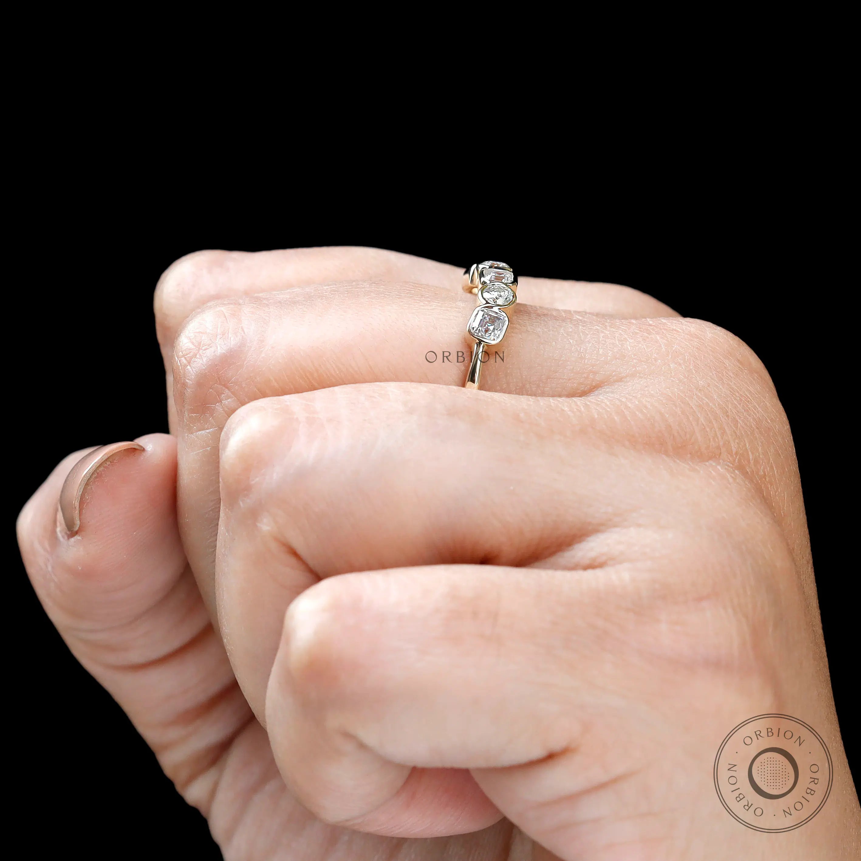 Top view on hand showing five-stone alternating moissanite design.