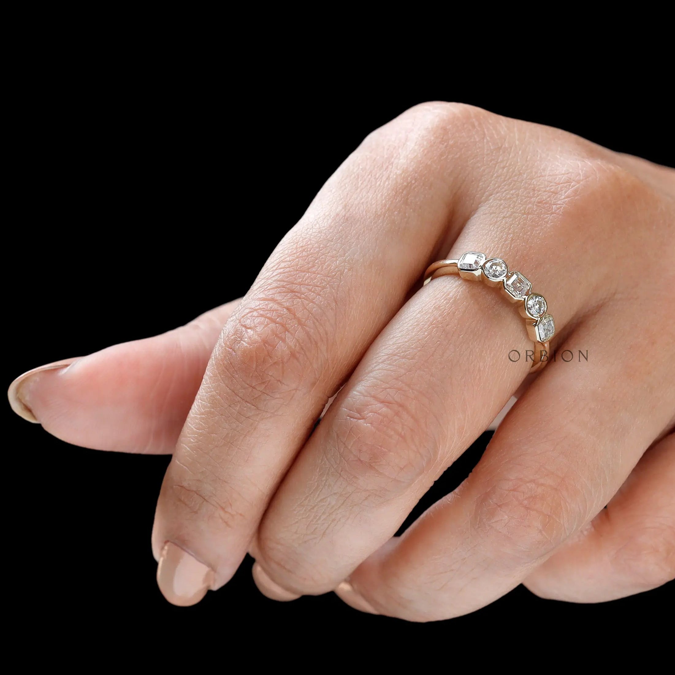 Angled hand shot highlighting bezel details and bright moissanite fire.