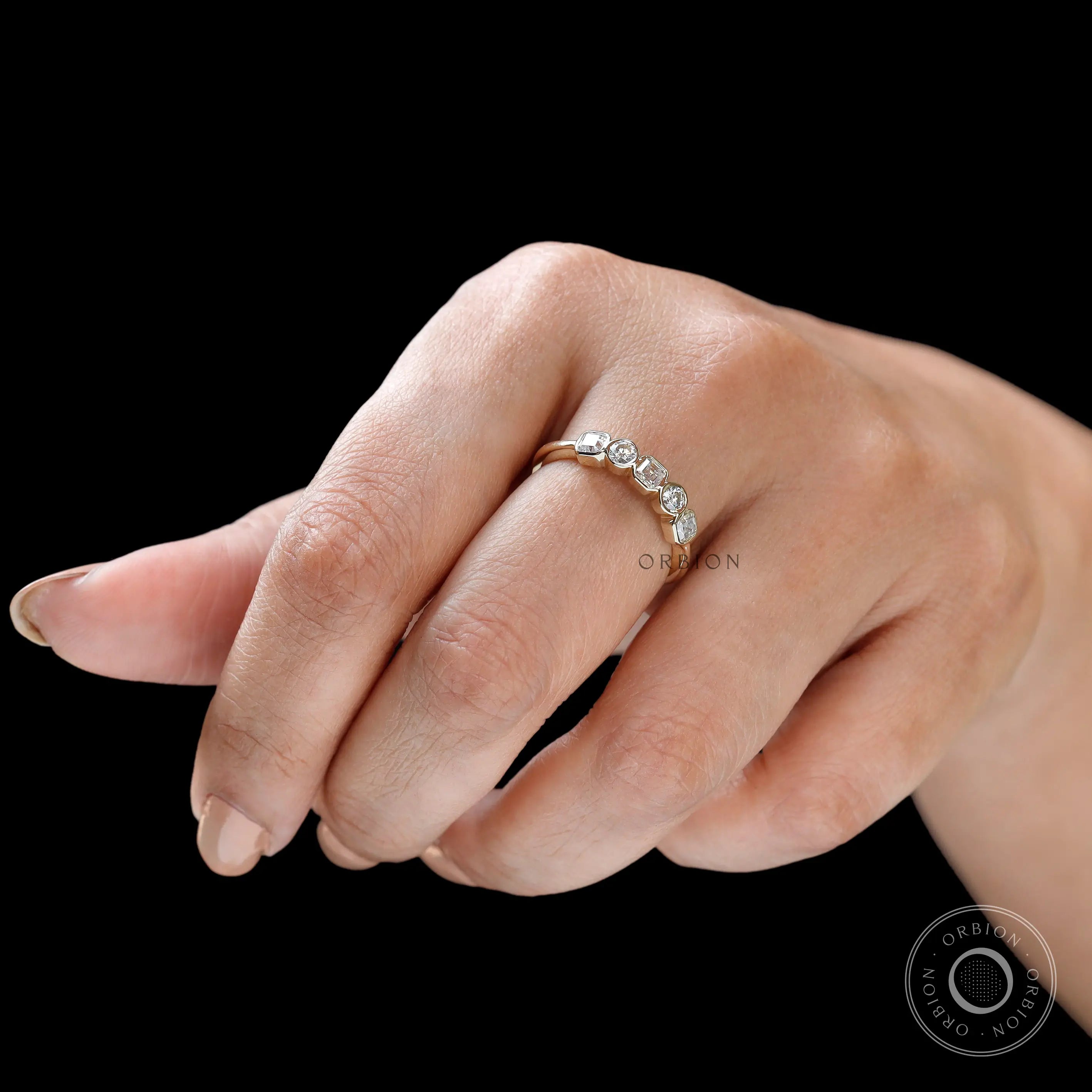 Angled hand shot highlighting bezel details and bright moissanite fire.