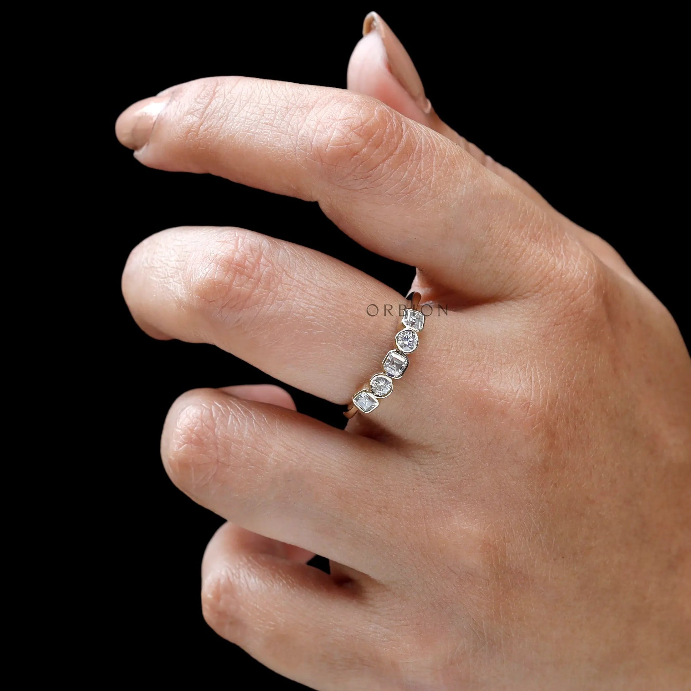 Close-up on hand showing refined bezels and minimalist stacking style.