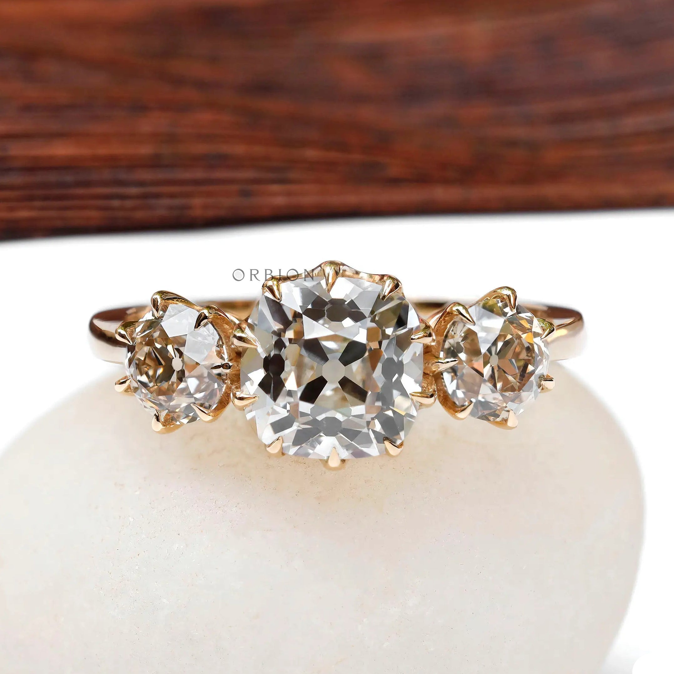 Front view three-stone vintage ring on white pebble.
