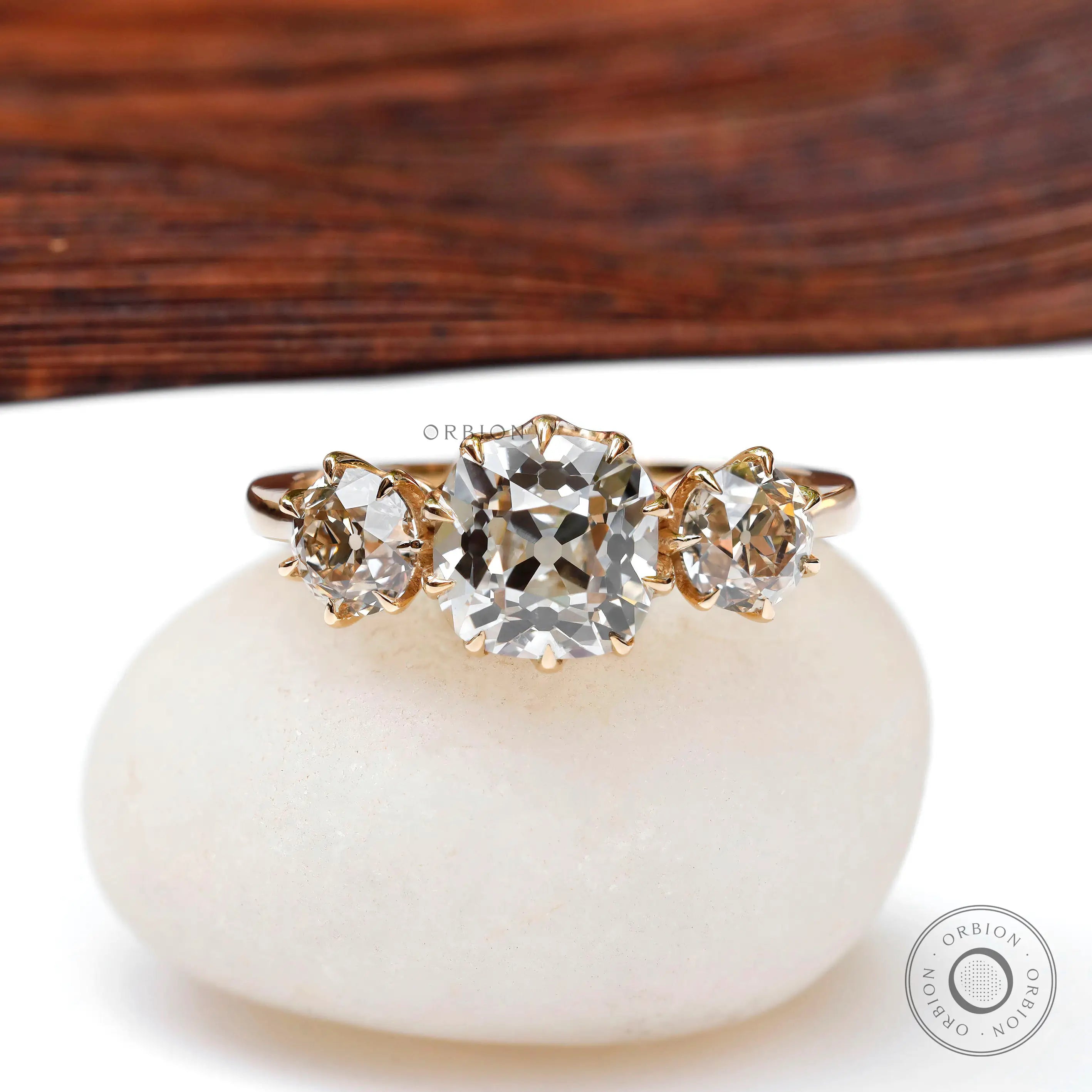 Front view three-stone vintage ring on white pebble.