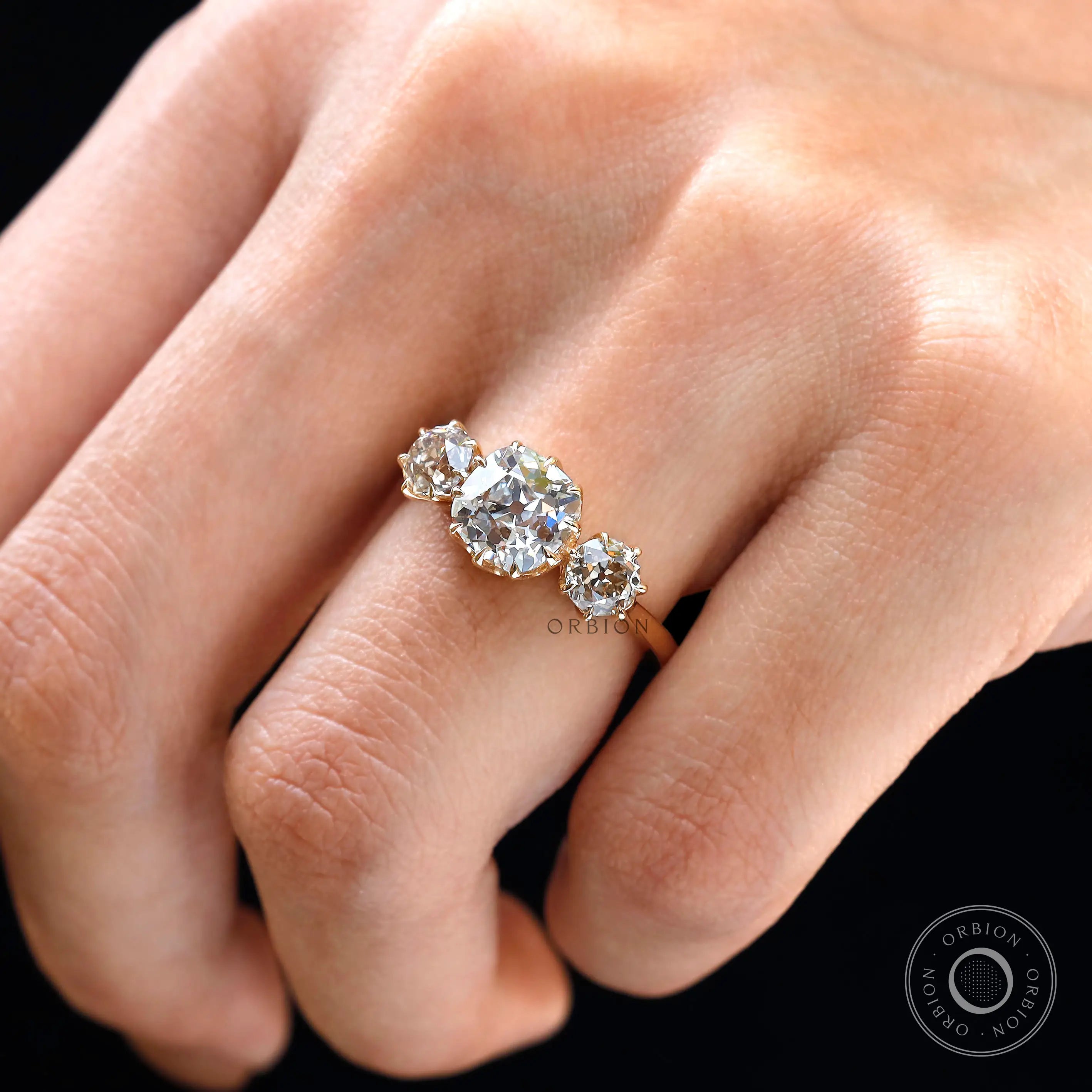 On-hand top view showing trilogy stones across band.