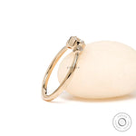 Dainty three stone moissanite ring displayed on white stone