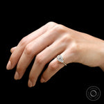On-hand top view of vintage inspired Asscher three stone ring against black background