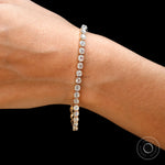 Dainty OMC cushion moissanite tennis bracelet on wrist in yellow gold