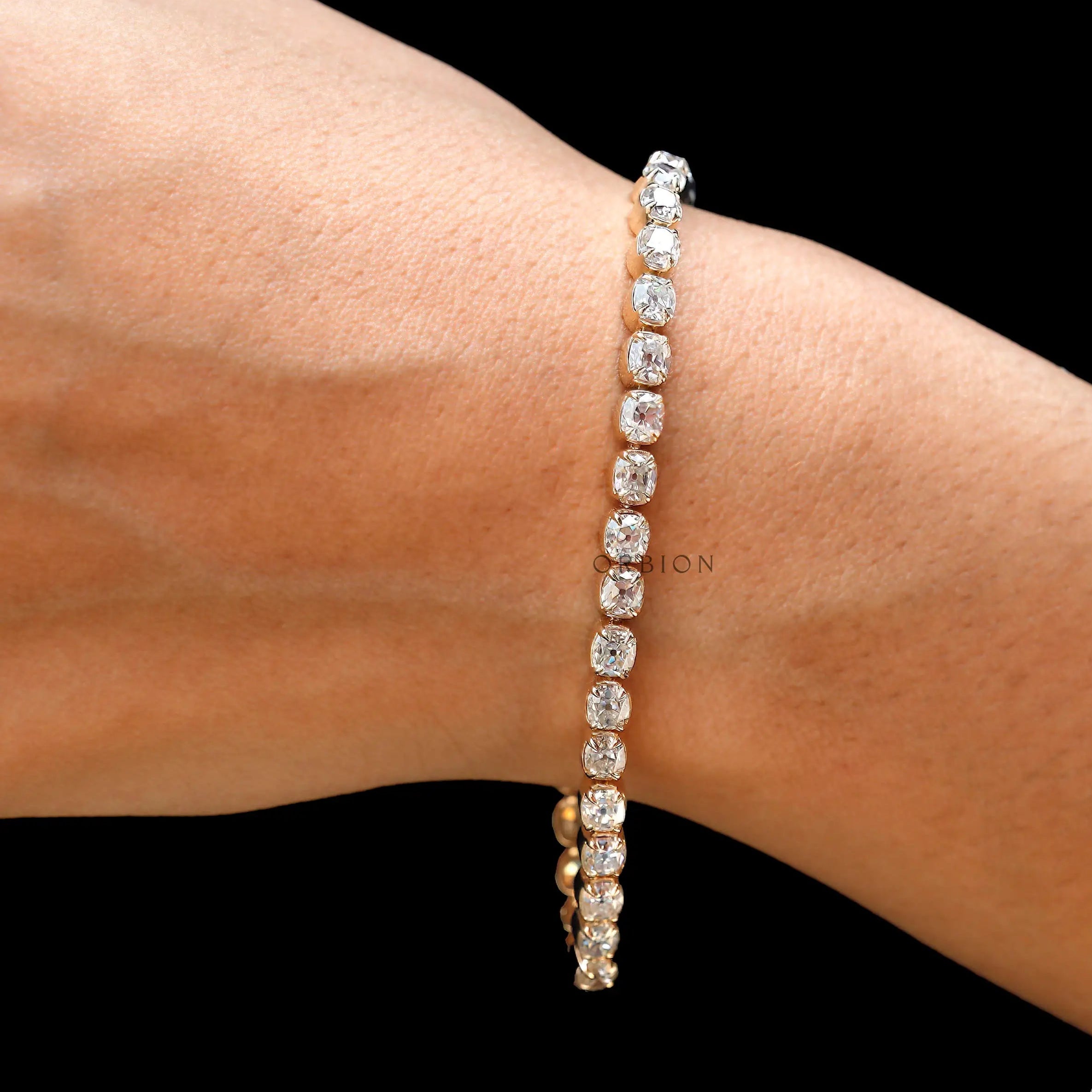 Dainty OMC cushion moissanite tennis bracelet on wrist in yellow gold
