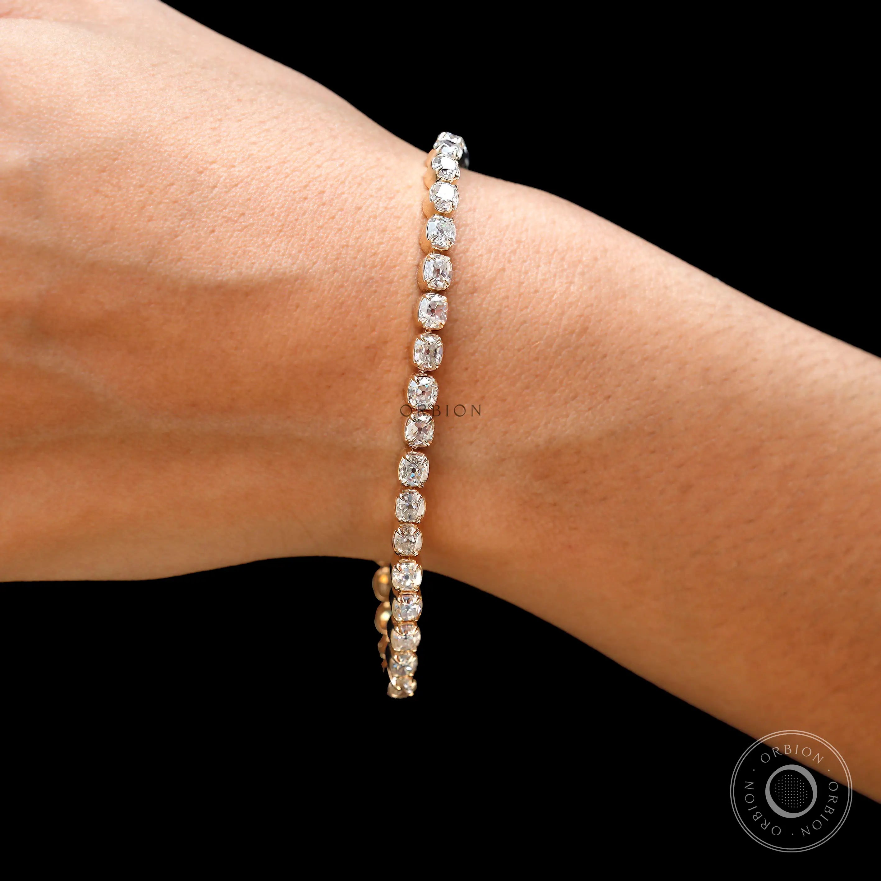 Dainty OMC cushion moissanite tennis bracelet on wrist in yellow gold